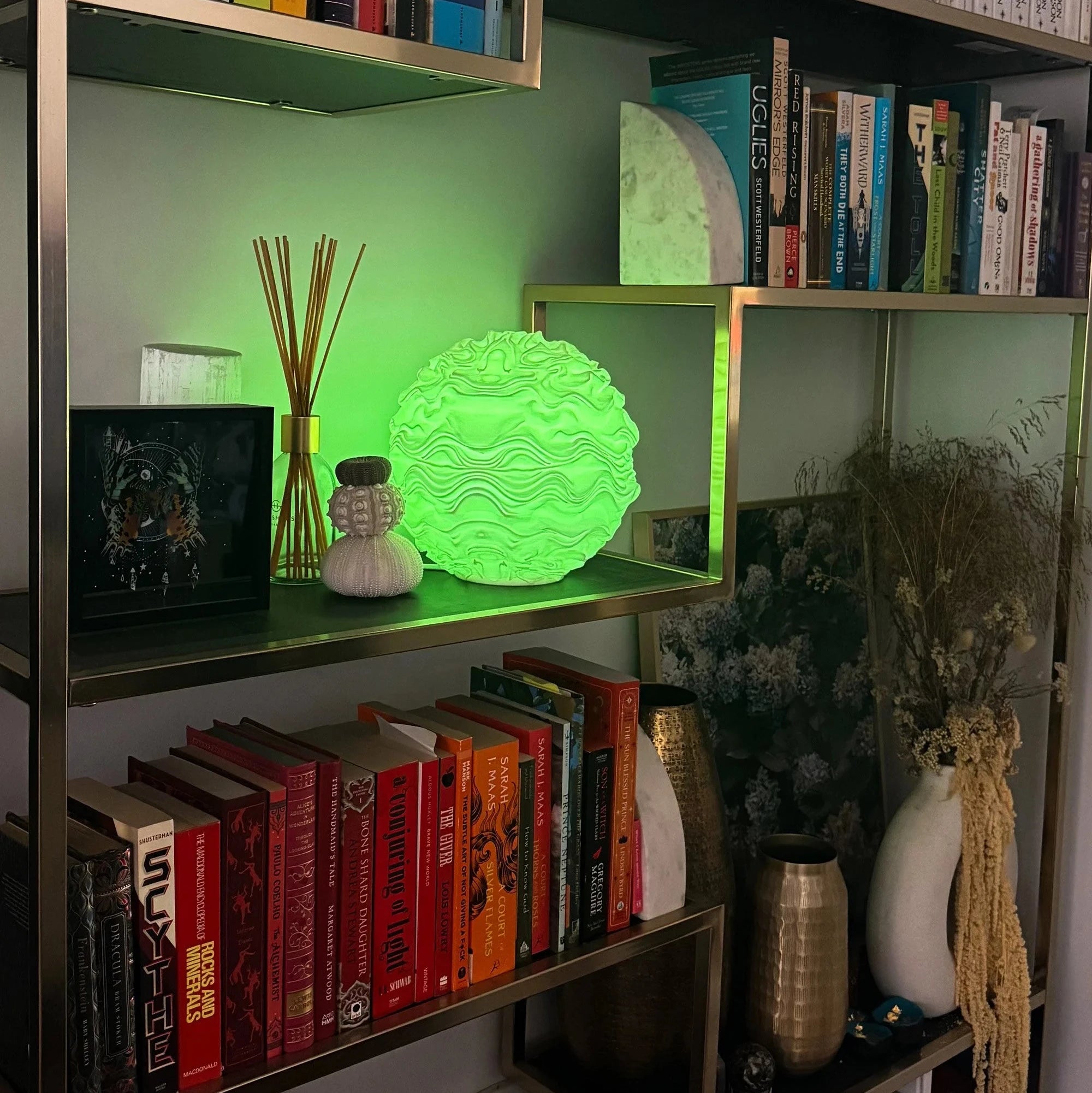 Noctis Studio Syzygy Lamp with sleek modern design, shown on a wooden surface with a textured background.
