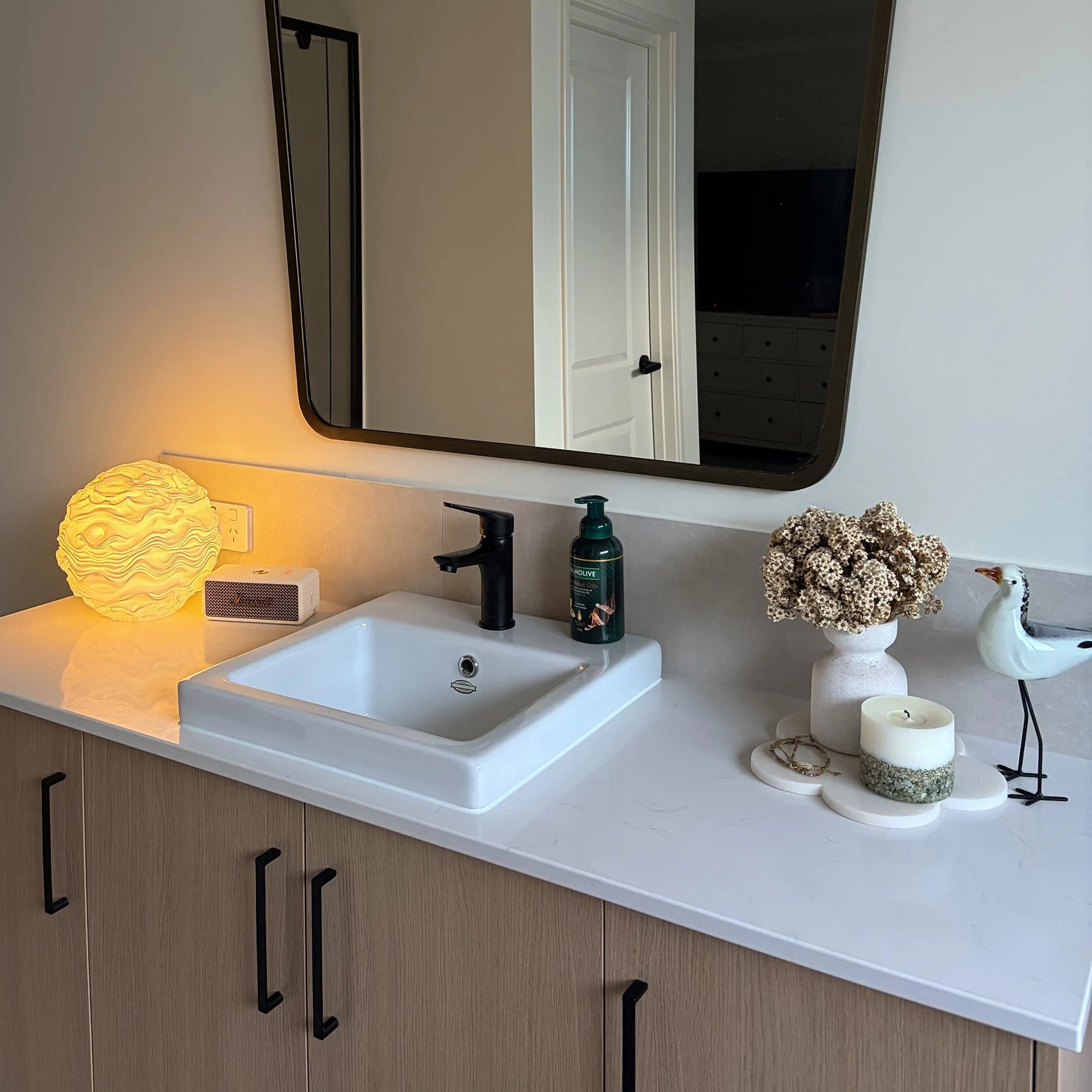 Noctis Studio Syzygy Lamp with sleek modern design, featuring smooth curves and a minimalist aesthetic, placed on a bathroom surface.