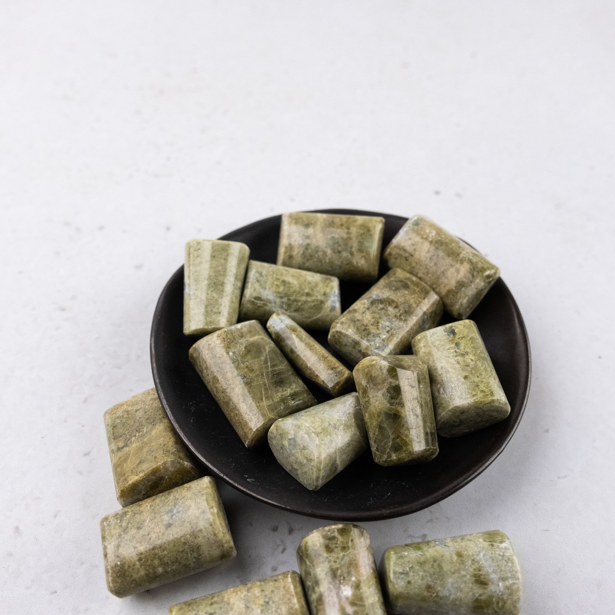 Vesonite tumble stone from Noctis Studio showing smooth, polished mineral with a vibrant green hue and natural stone texture.