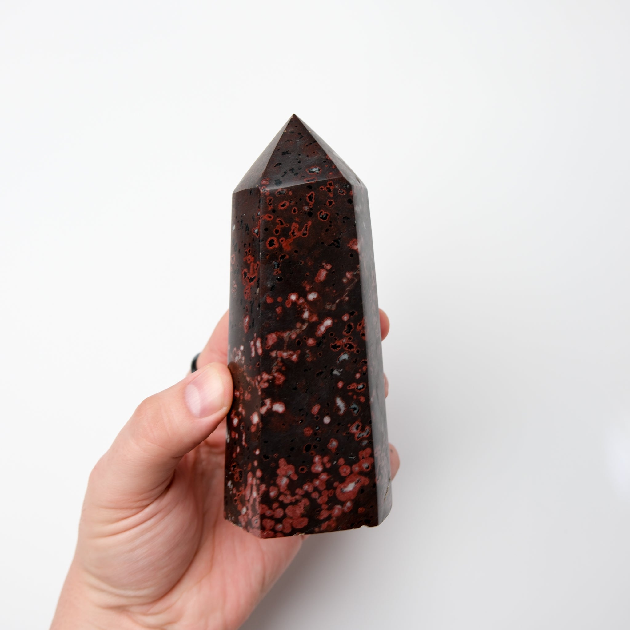 Cinnabar Peridotite pillar sculpture by Noctis Studio featuring a tall, polished stone pillar with rich red and green mineral tones.