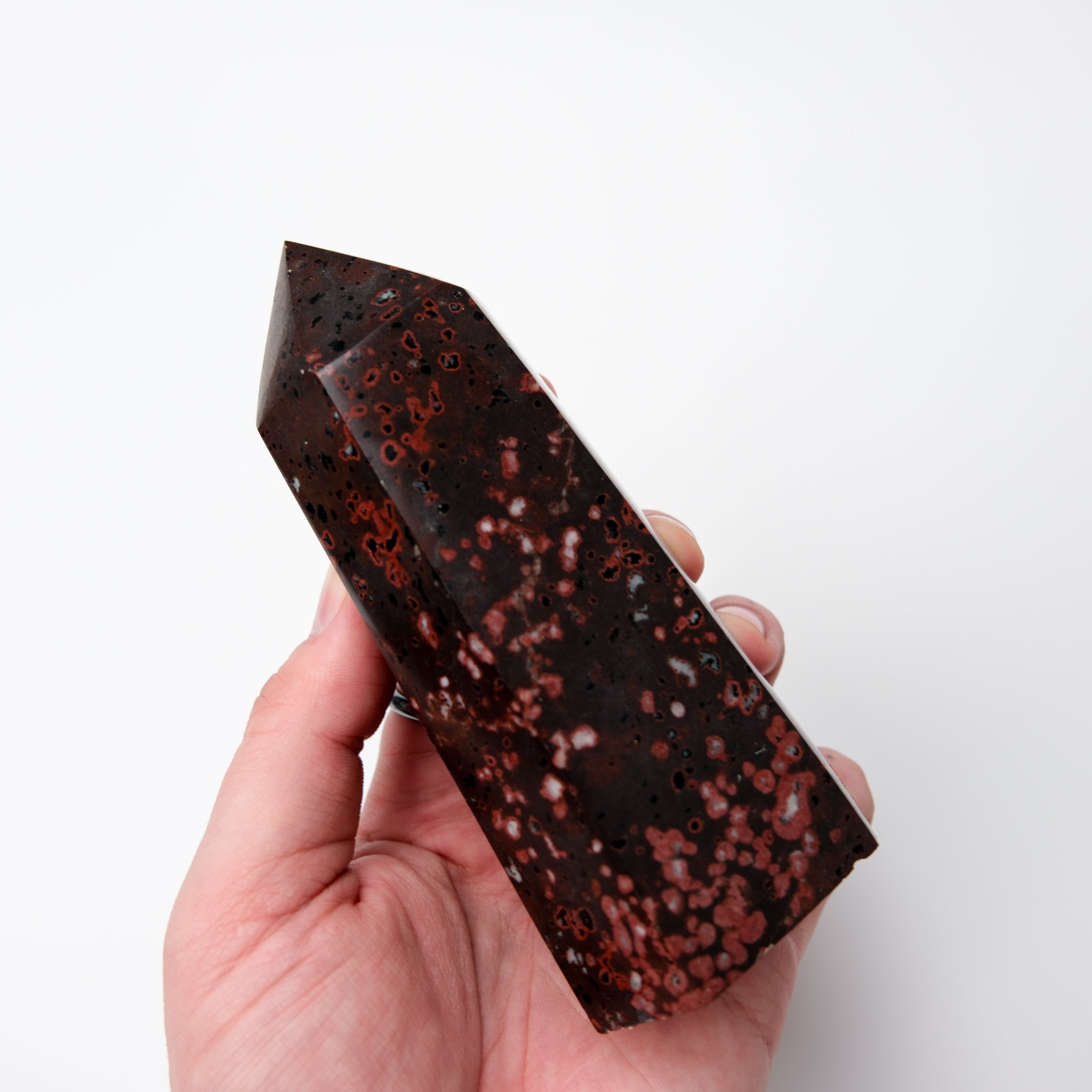 Cinnabar Peridotite pillar sculpture by Noctis Studio, showcasing a tall, polished stone pillar with rich reddish and green mineral tones.