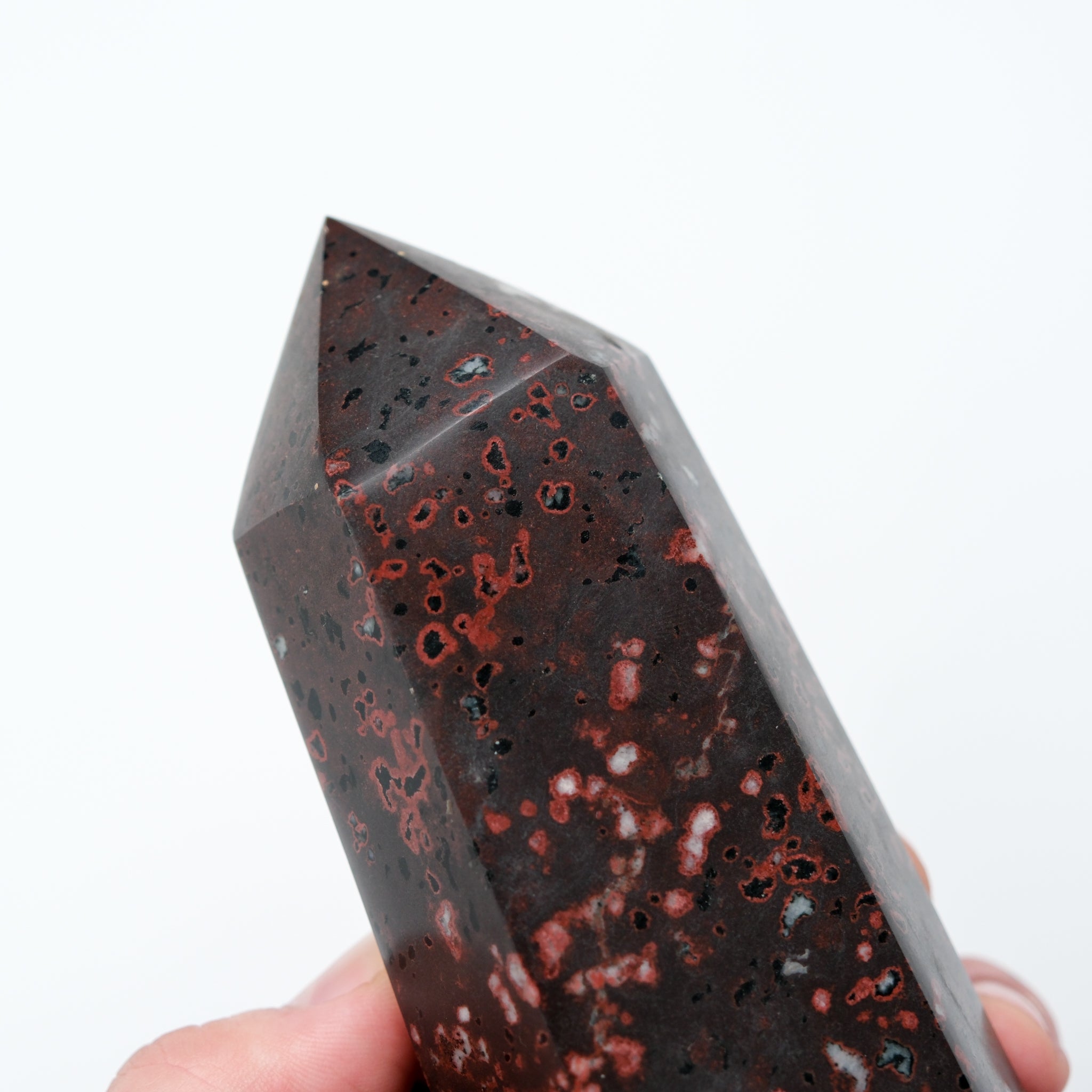 Cinnabar Peridotite pillar sculpture by Noctis Studio, showing a tall, polished stone pillar with rich red and green mineral patterns.