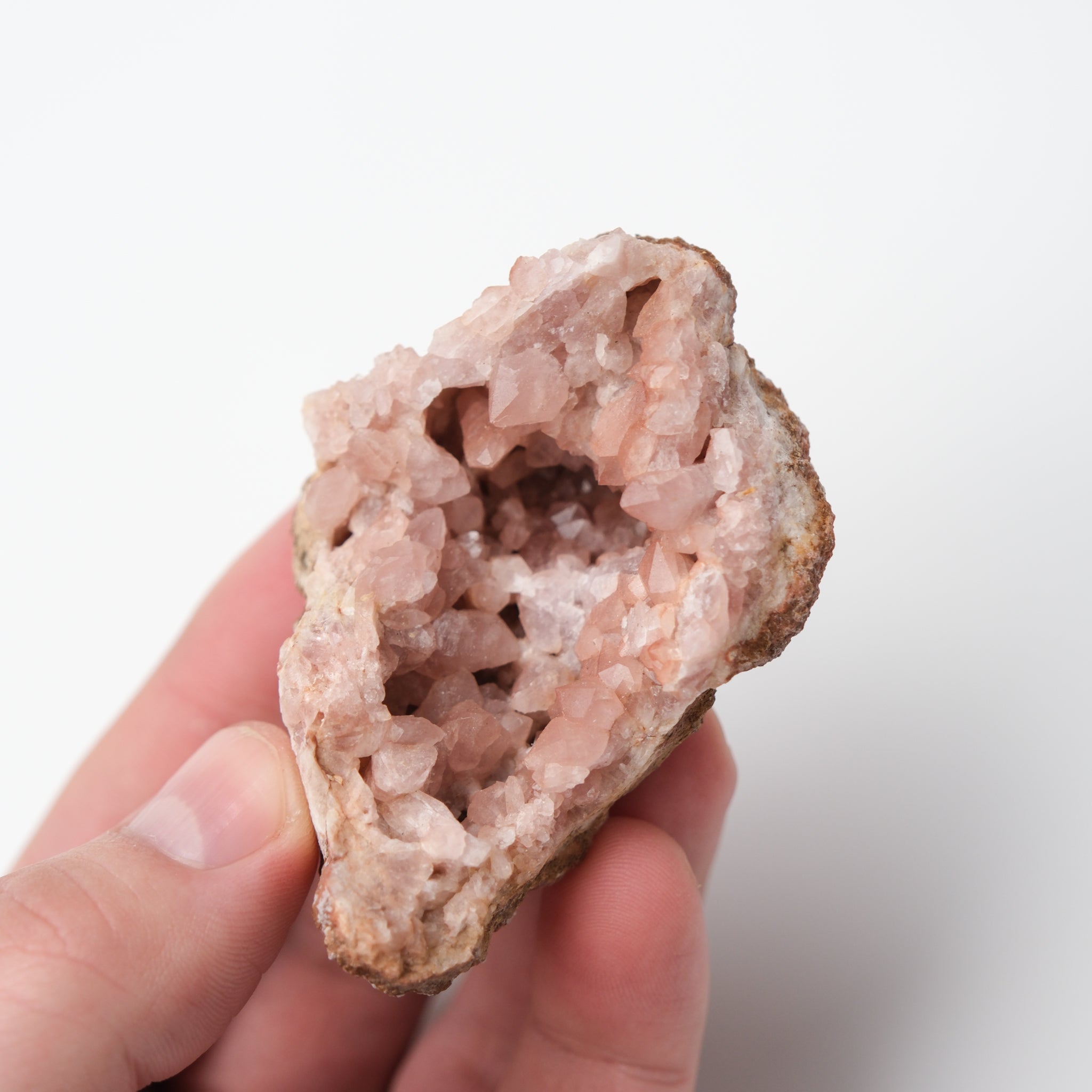 Pink Amethyst geode from Noctis Studio showcasing crystalline purple interior and rough exterior on a white background.