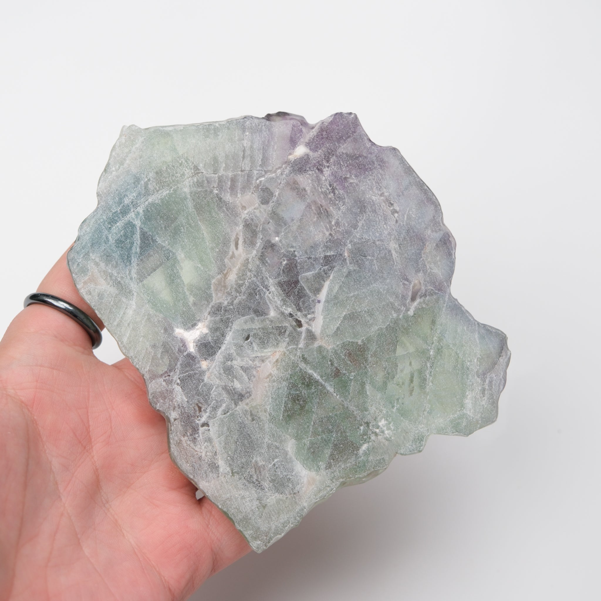 Noctis Studio fluorite slab showing vibrant green and purple mineral layers with polished, smooth surface and natural crystal patterns.