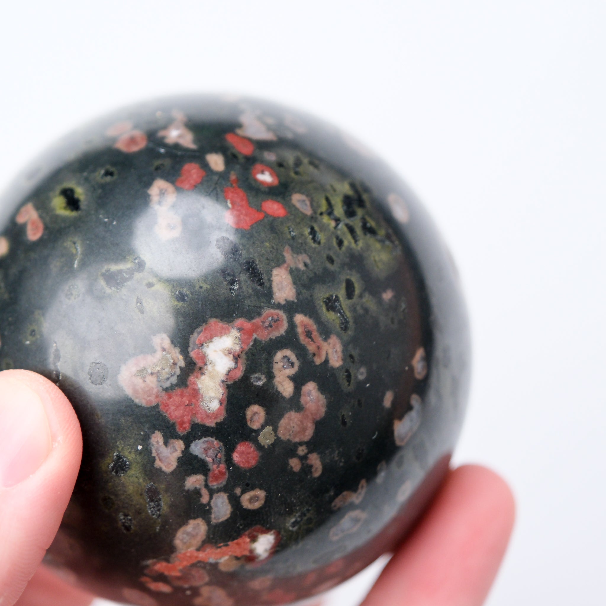 Cinnabar Peridotite sphere from Noctis Studio showcasing a smooth, rounded mineral ball with rich cinnabar and green peridotite tones.