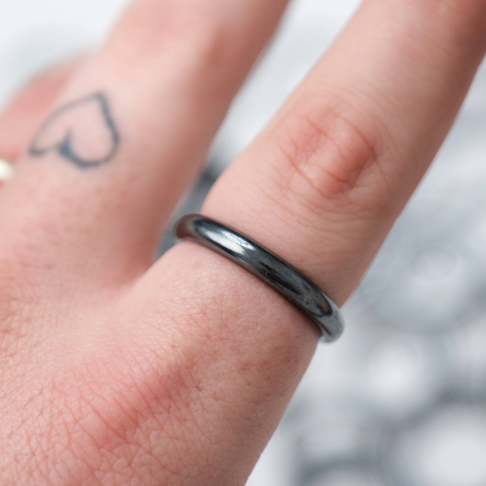 Two hematite rings displayed on crystal stands, featuring sleek, polished black stone designs by Noctis Studio.