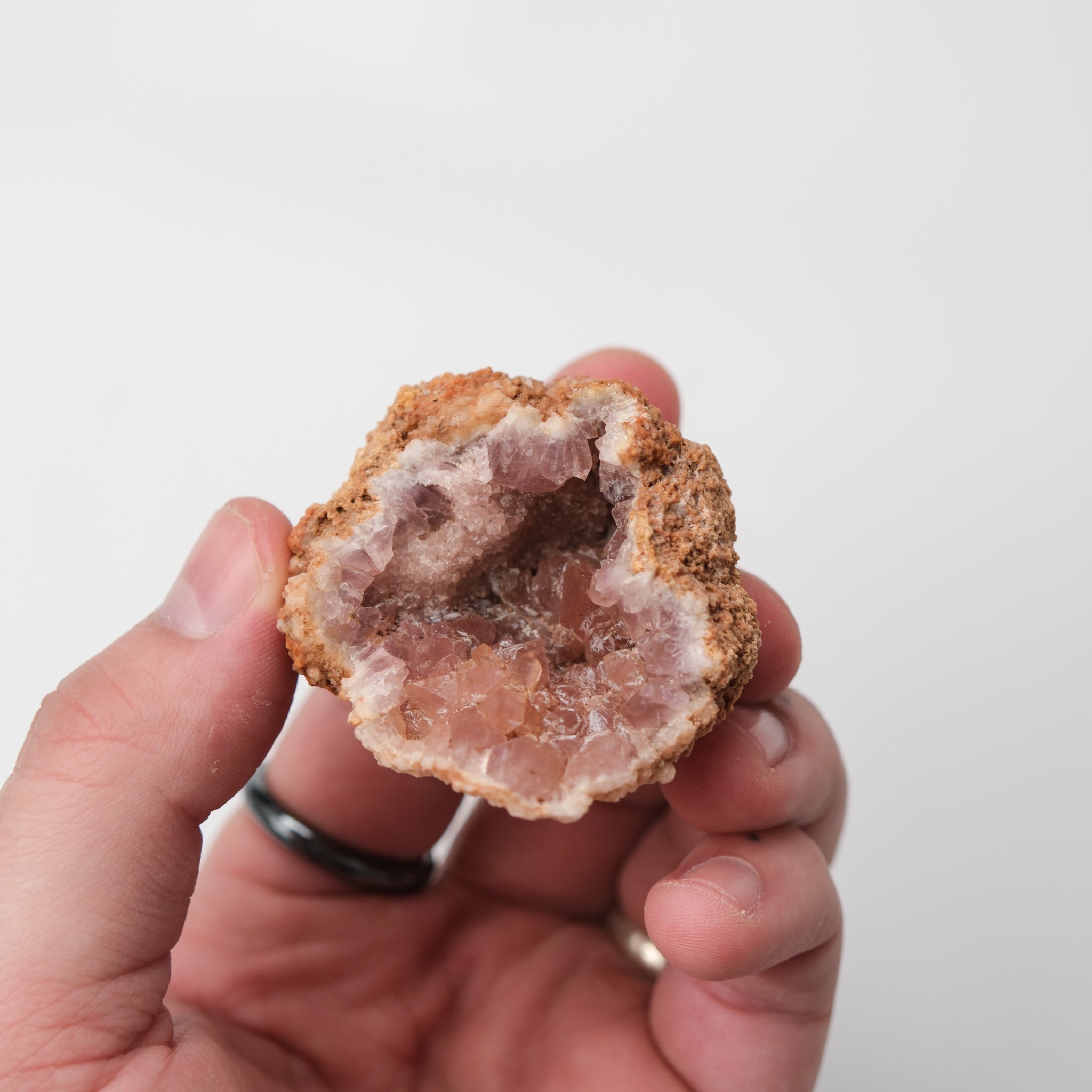 Pink Amethyst geode from Noctis Studio with sparkling purple crystals and rocky exterior, showcasing natural mineral beauty.