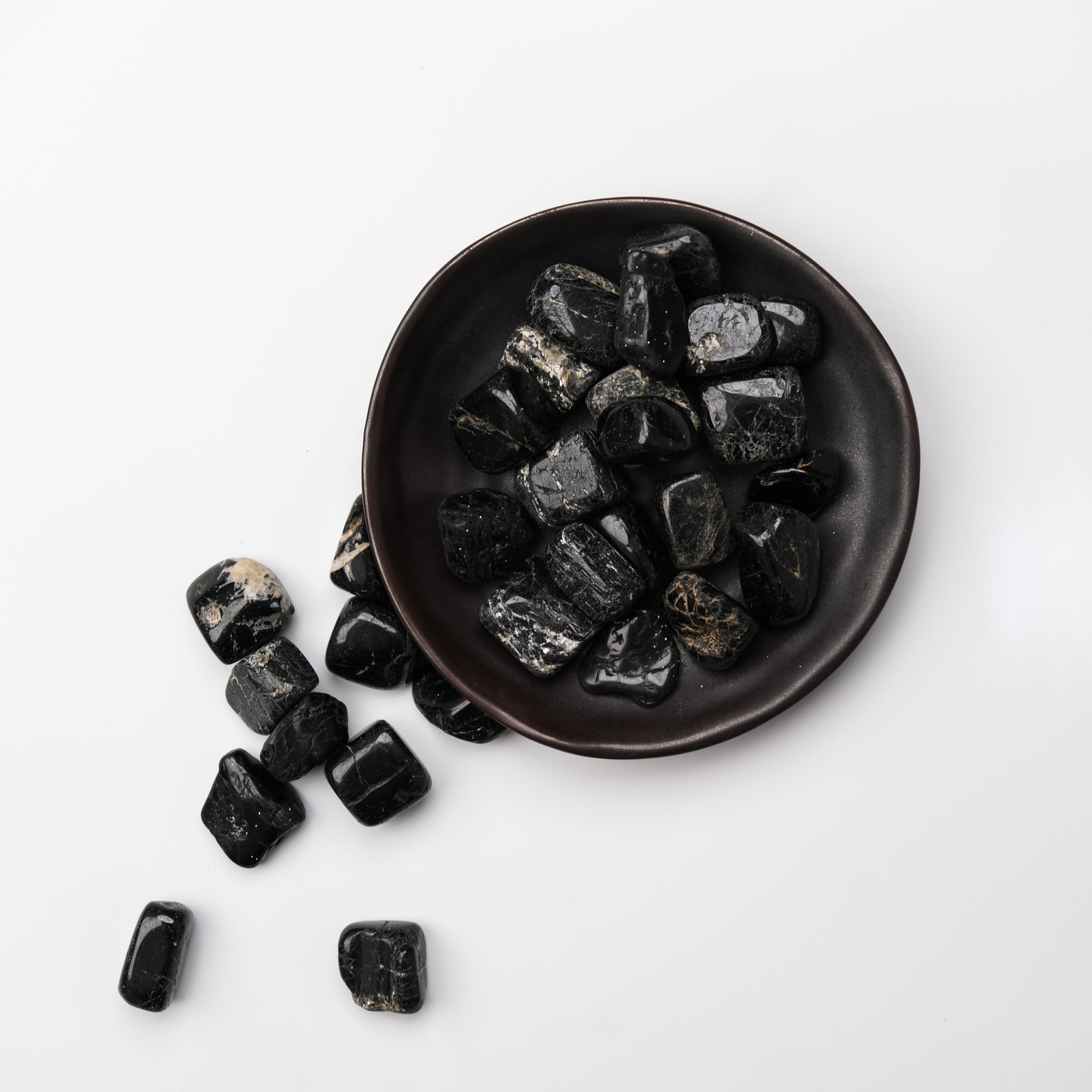 Black Tourmaline tumble stone from Noctis Studio, polished mineral gem with a smooth, shiny black surface and natural crystalline texture.