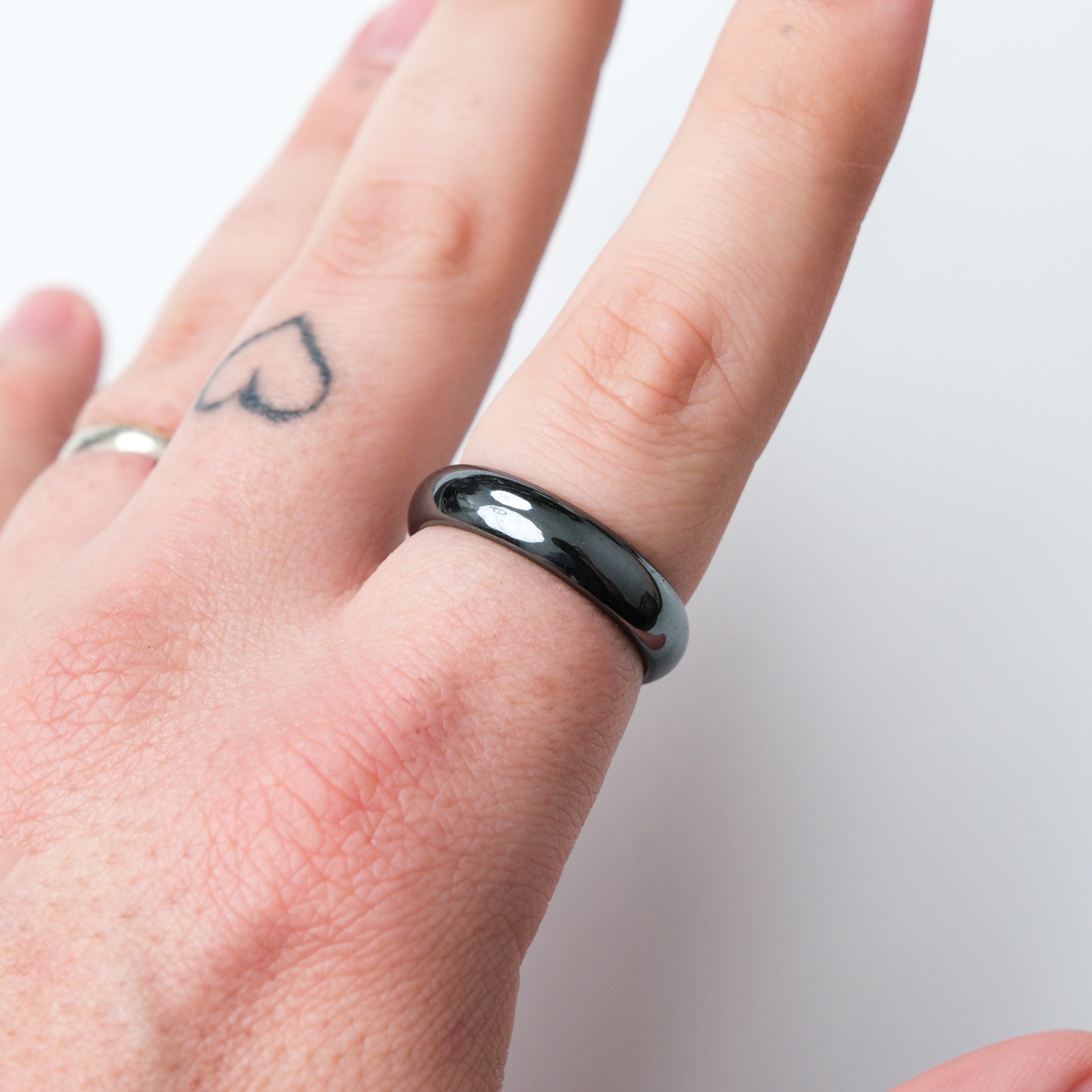 Two hematite rings displayed on crystal stands, featuring sleek black metallic finish, from Noctis Studio's jewelry collection.
