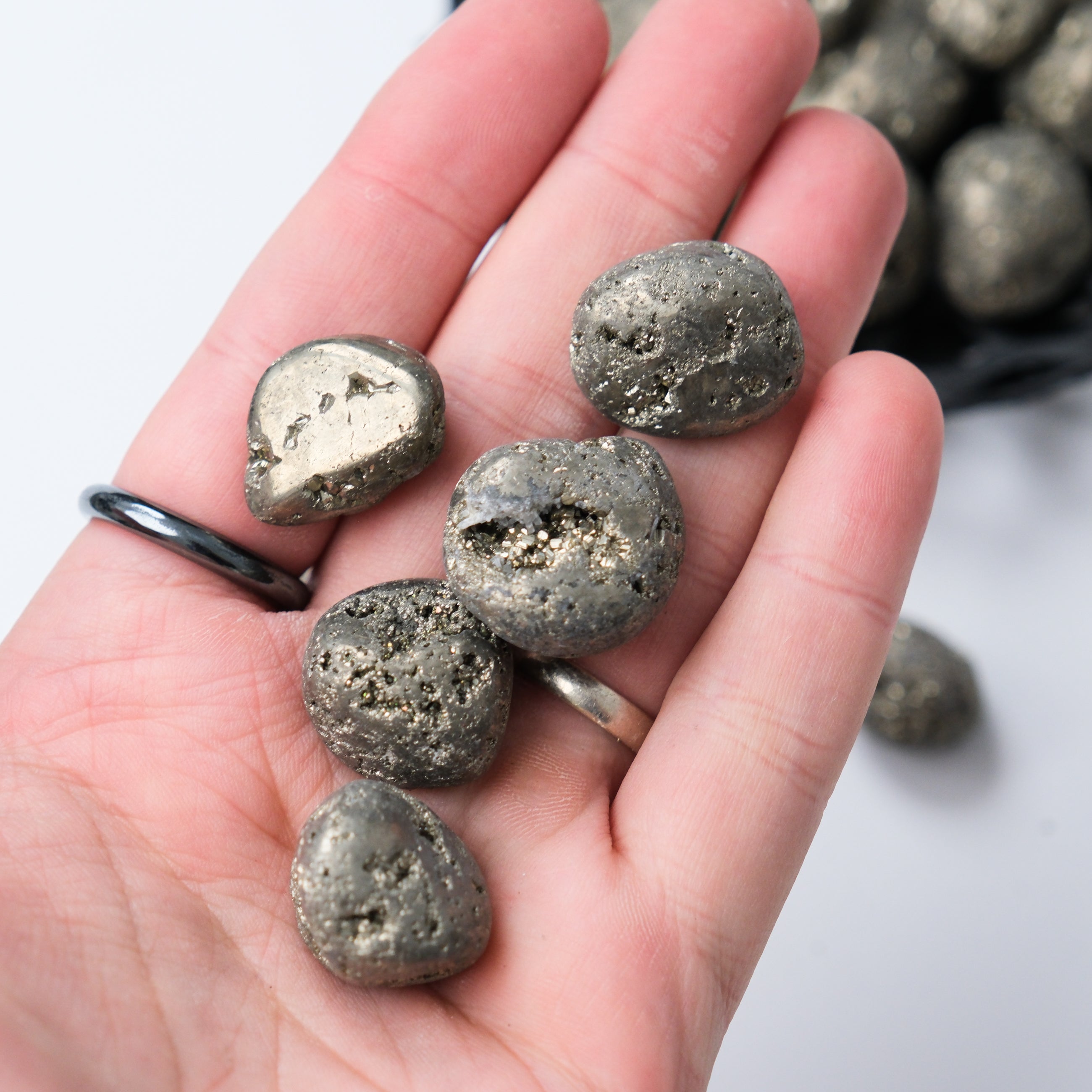 Noctis Studio pyrite tumble stone, natural mineral with metallic luster and cubic crystal formations, on a neutral background.