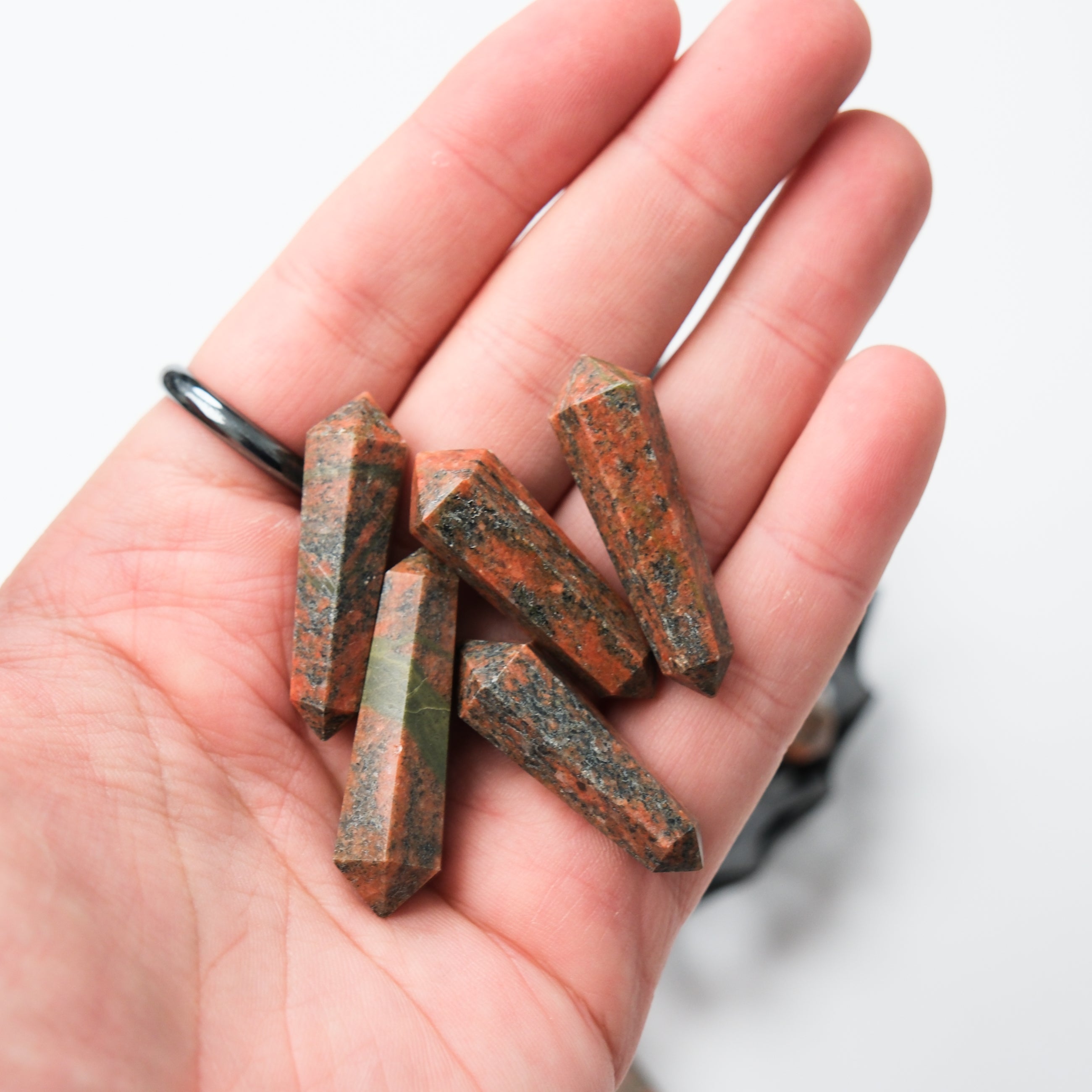 Unakite double gridding point by Noctis Studio, featuring a polished green and pink stone with metal accents for crystal healing.