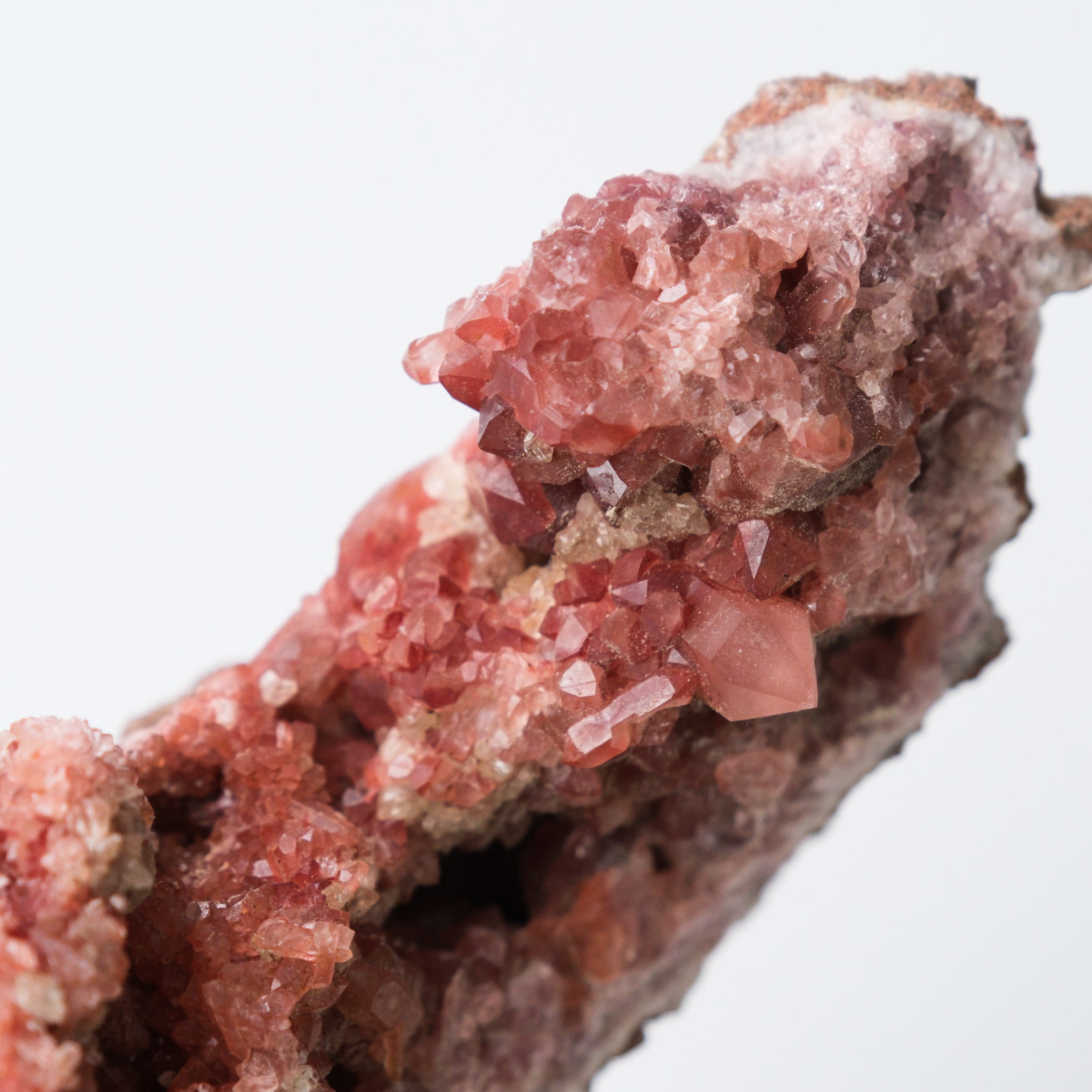 Pink Amethyst geode by Noctis Studio showing vibrant purple crystals and a textured outer shell on a neutral background.