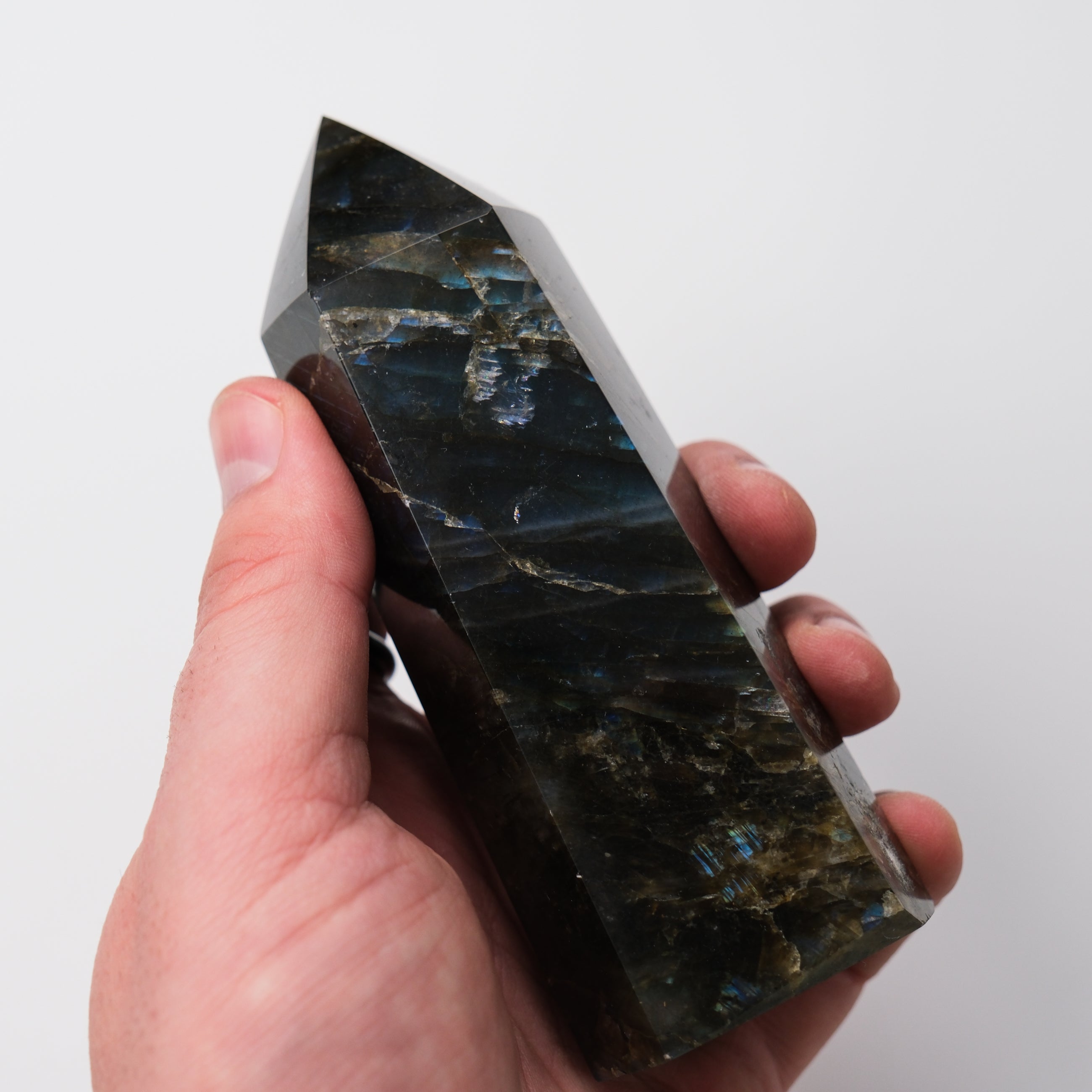 Labradorite pillar sculpture by Noctis Studio showcasing iridescent blue and green hues on a smooth stone surface.