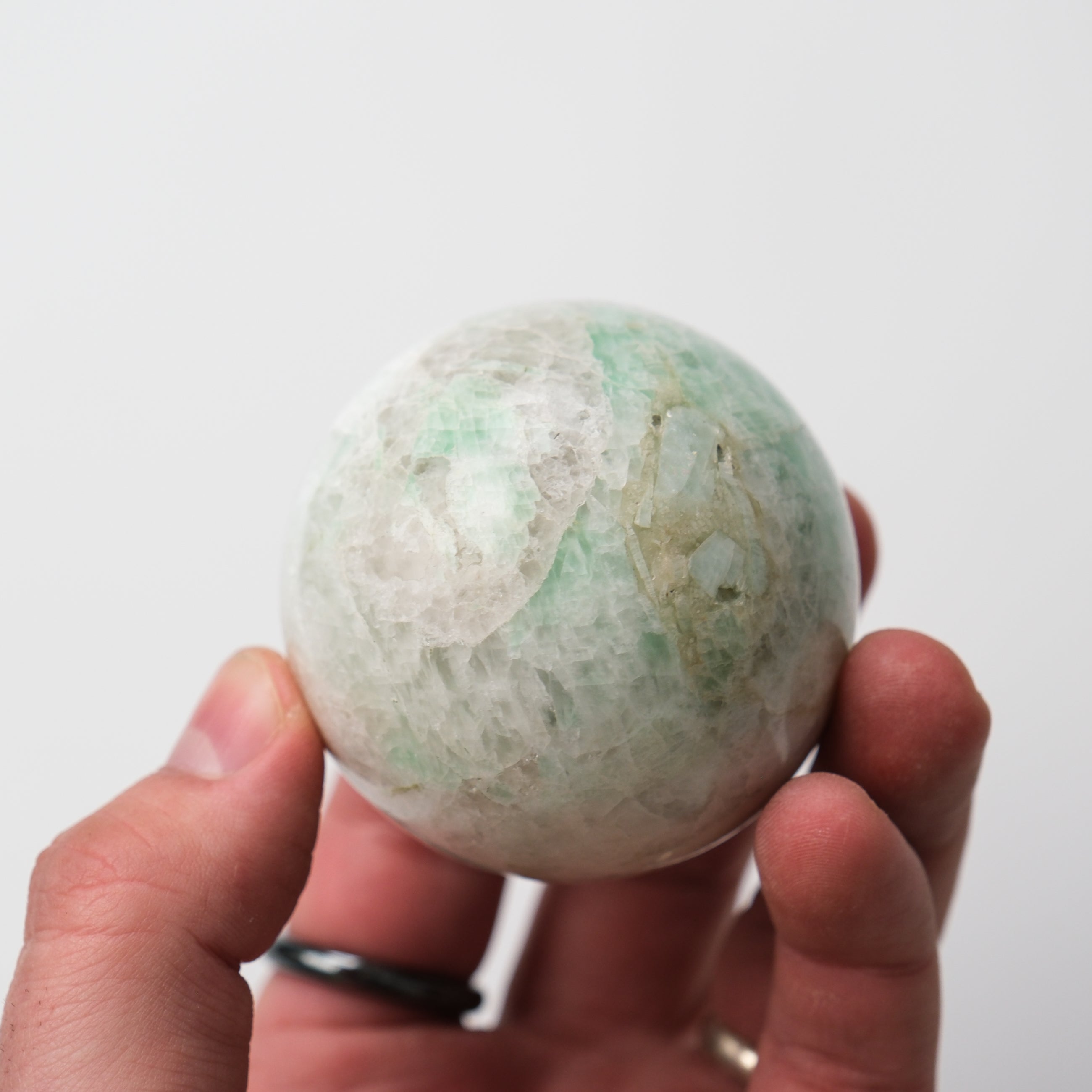 Green moonstone sphere by Noctis Studio showing a smooth, polished gemstone with a glowing green shimmer.