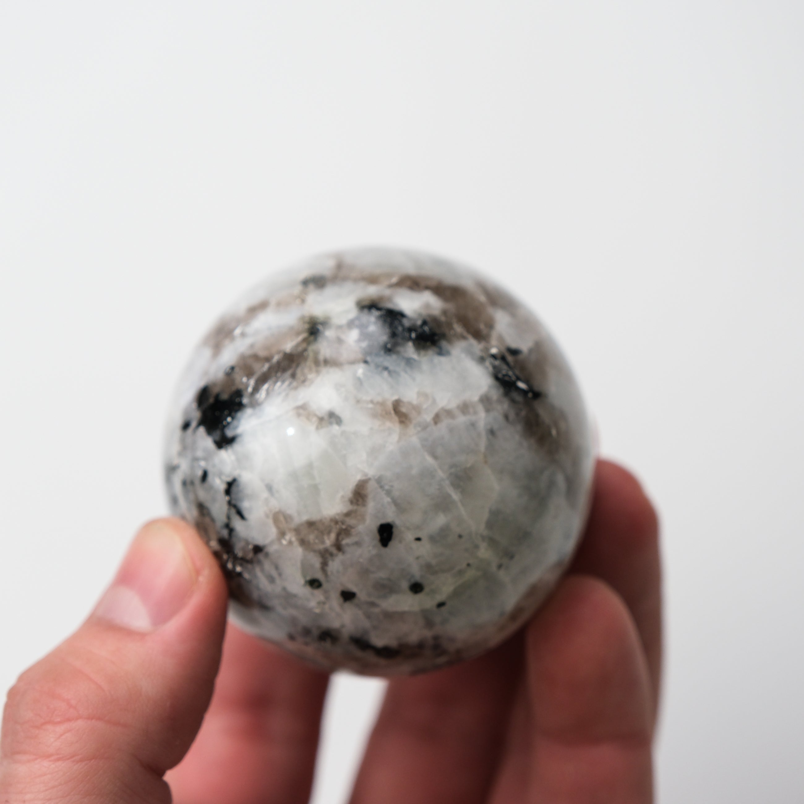 Noctis Studio moonstone sphere showing a smooth, polished gemstone with luminous, iridescent surface on a neutral background.