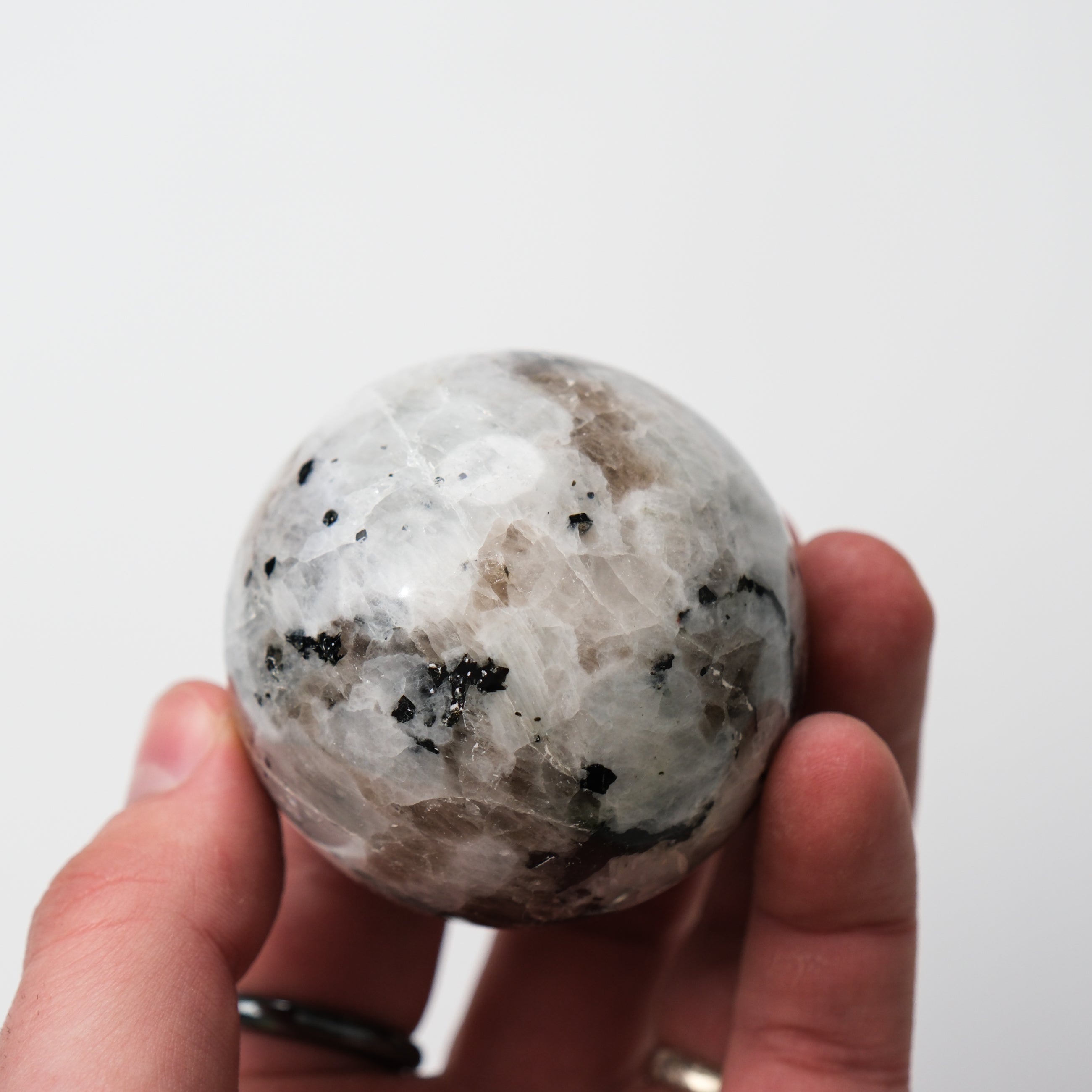 Noctis Studio moonstone sphere resting on a surface, showcasing the smooth, polished gemstone with subtle blue and white iridescence.