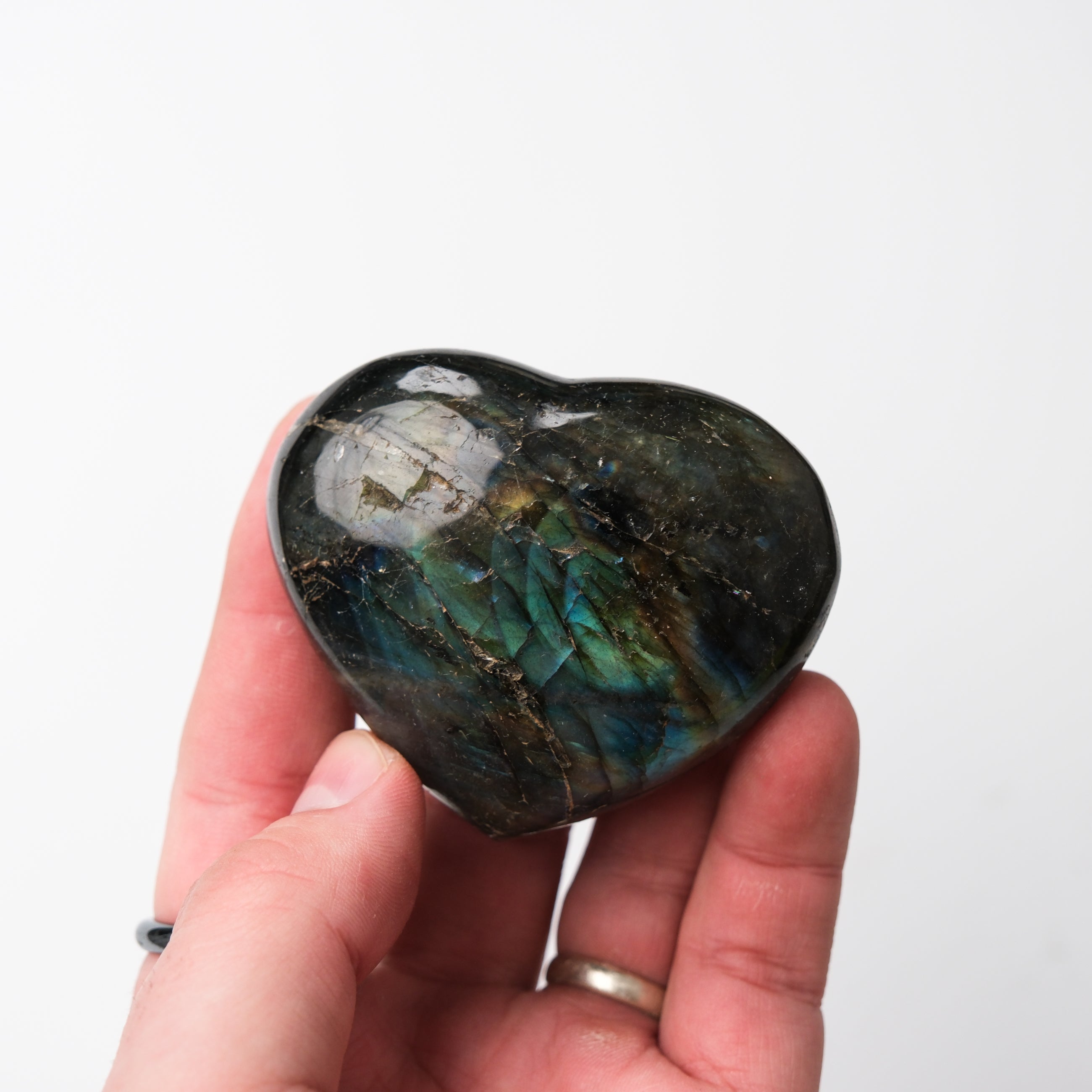 Polished Labradorite heart gemstone from Noctis Studio with iridescent blue and green flashes, smooth and shaped into a heart.