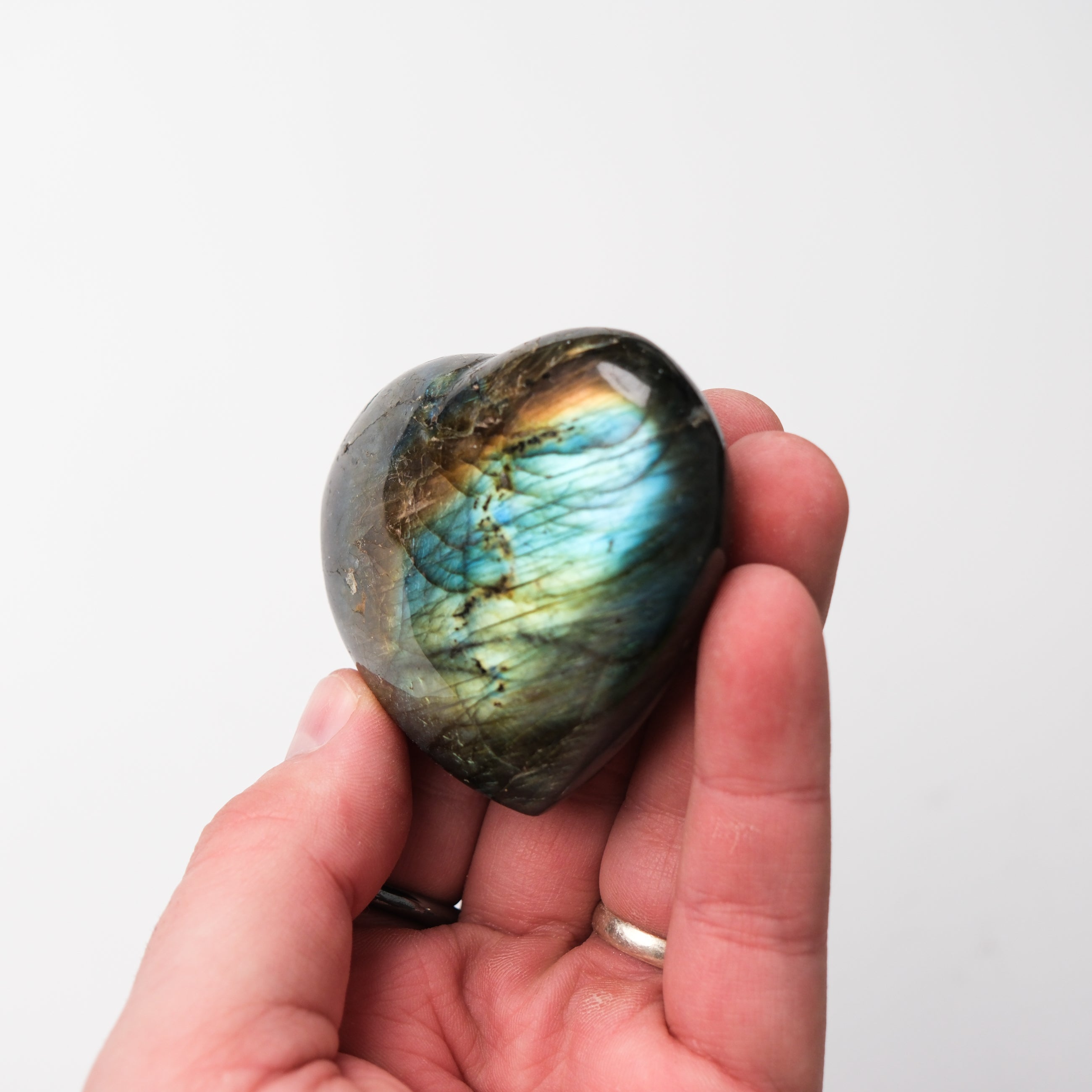 Labradorite heart gemstone sculpture by Noctis Studio, polished stone with iridescent flashes, smooth and heart-shaped.