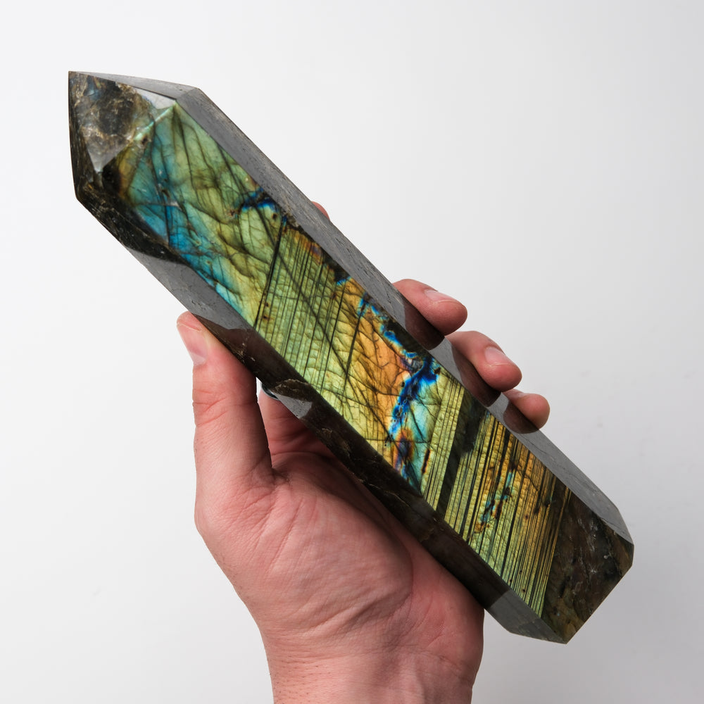 Labradorite pillar sculpture by Noctis Studio showcasing iridescent blue and green flash on polished stone surface.