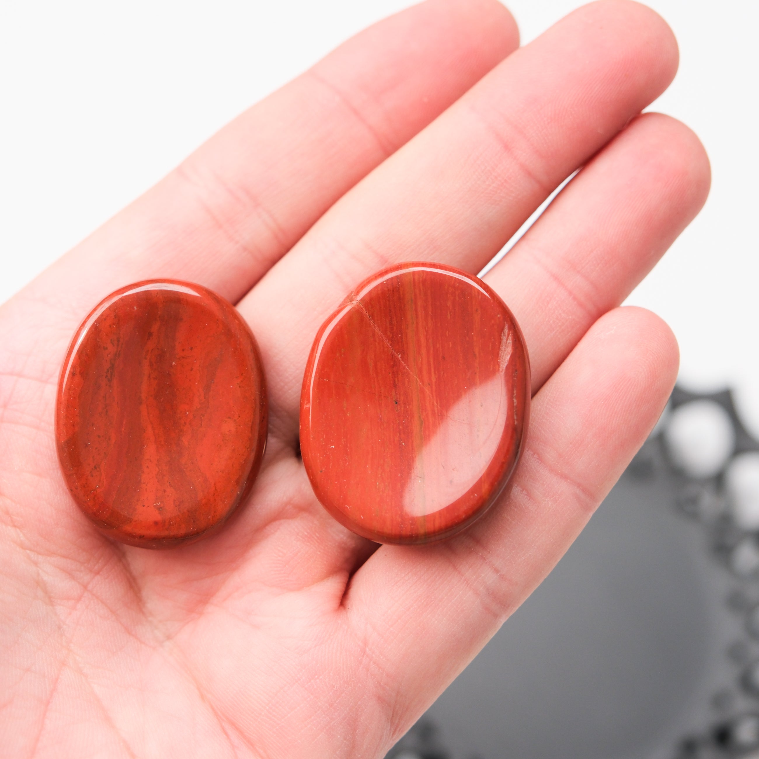 Red Jasper worry stone from Noctis Studio, smooth polished gemstone with rich red color and natural patterns, handheld for stress relief.