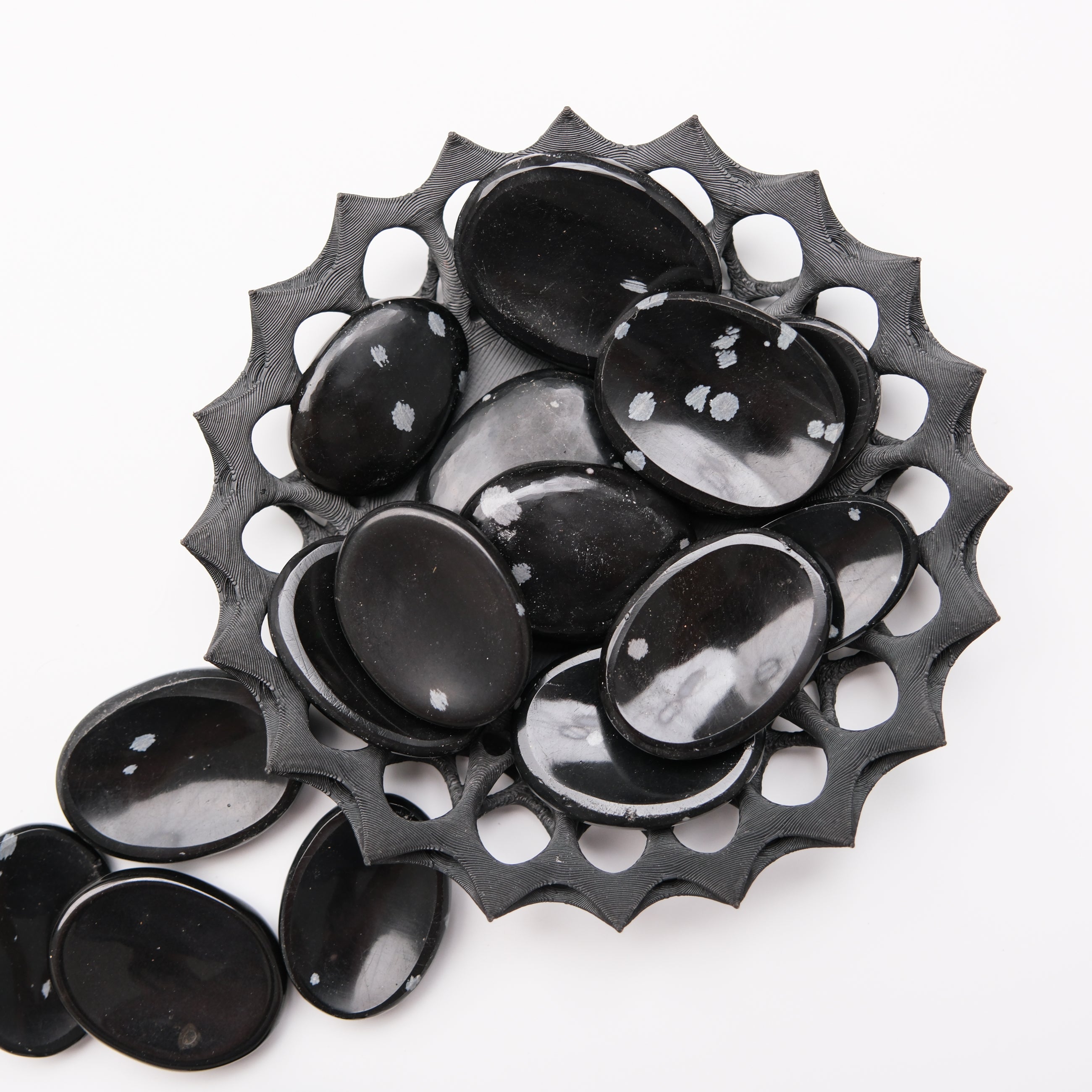 Snowflake Obsidian worry stone from Noctis Studio, smooth black gemstone with white snowflake patterns, used for stress relief.
