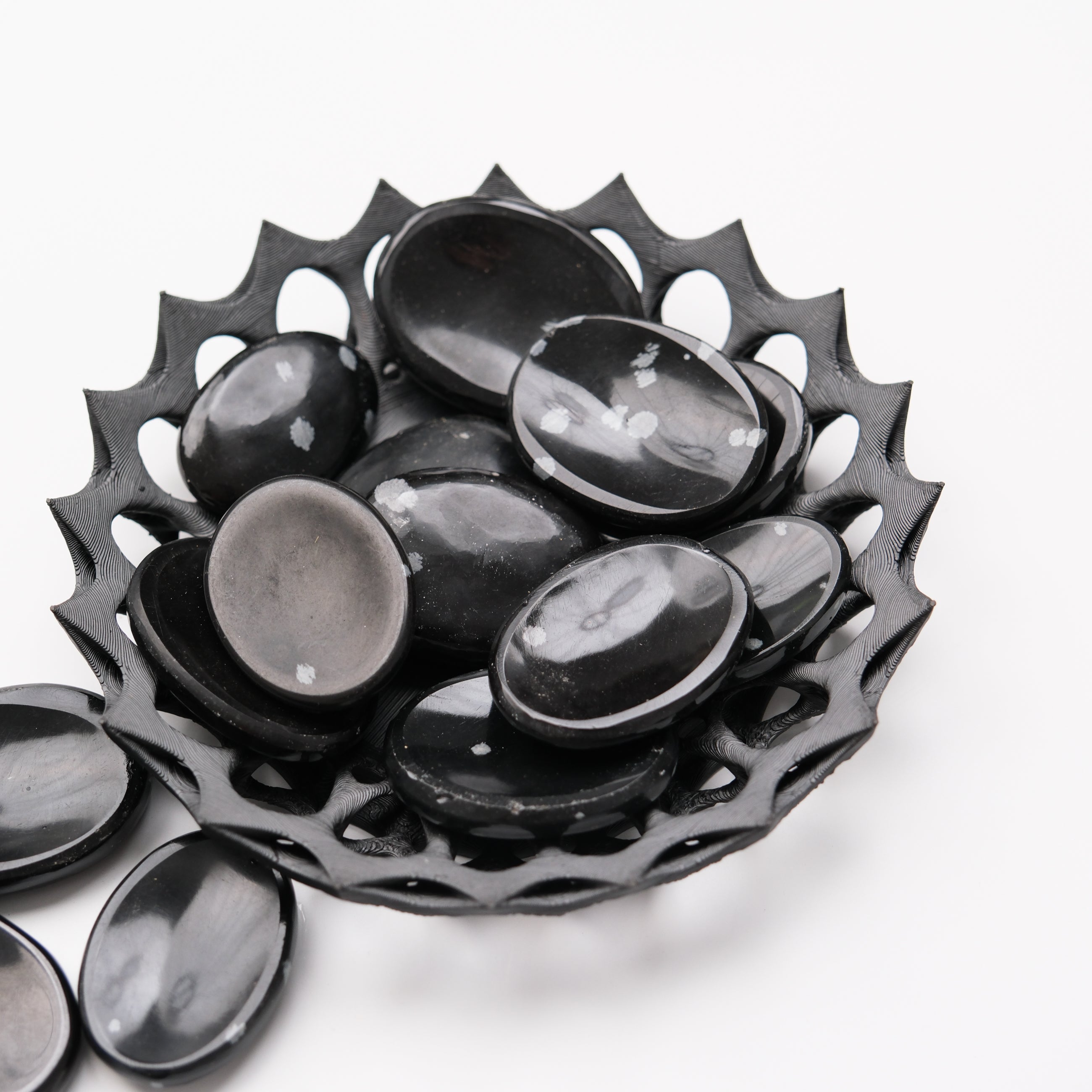 Snowflake Obsidian worry stone from Noctis Studio, smooth black gemstone with white snowflake-like patterns, handheld relaxation accessory.