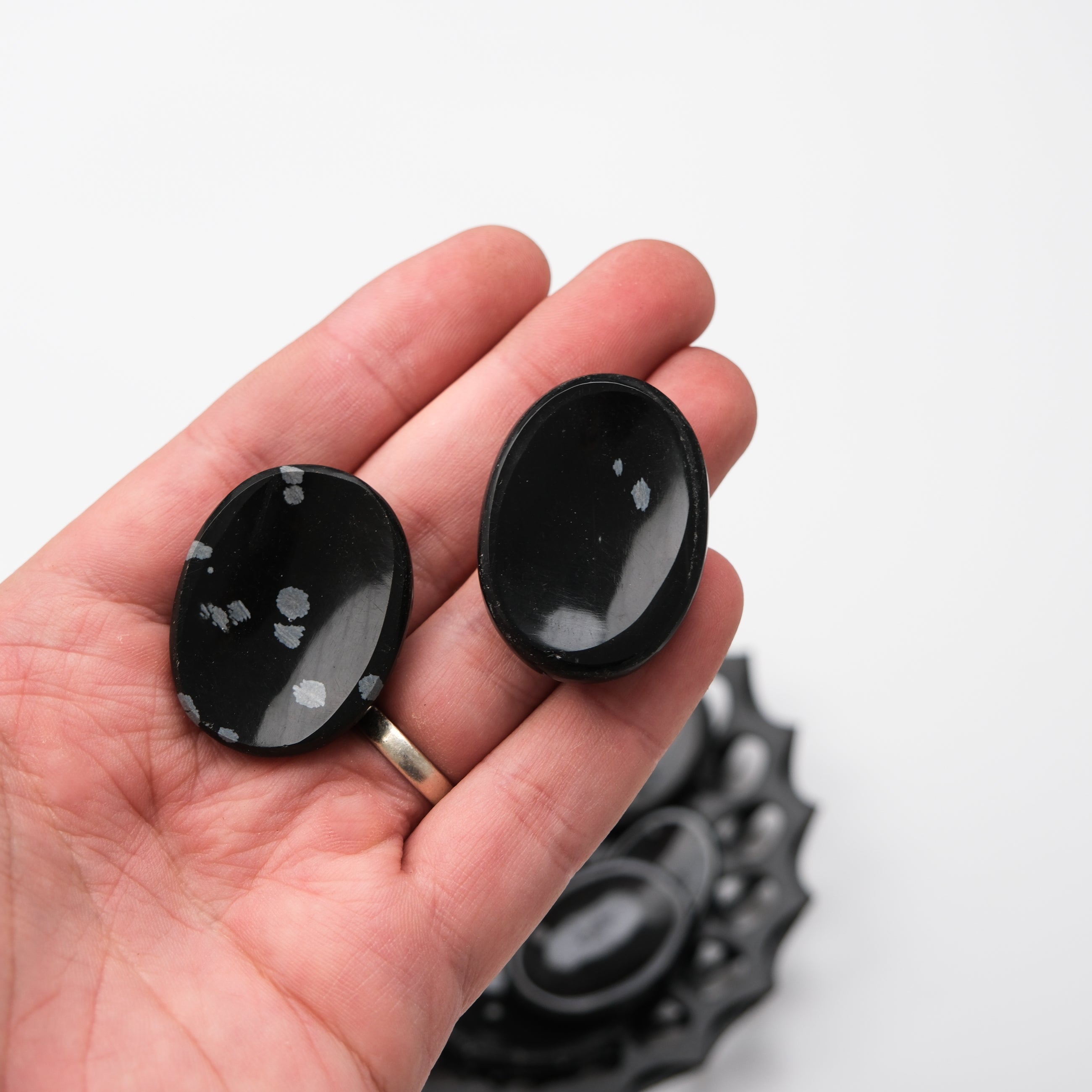 Snowflake Obsidian worry stone by Noctis Studio showing polished black stone with white snowflake patterns and smooth rounded edges.