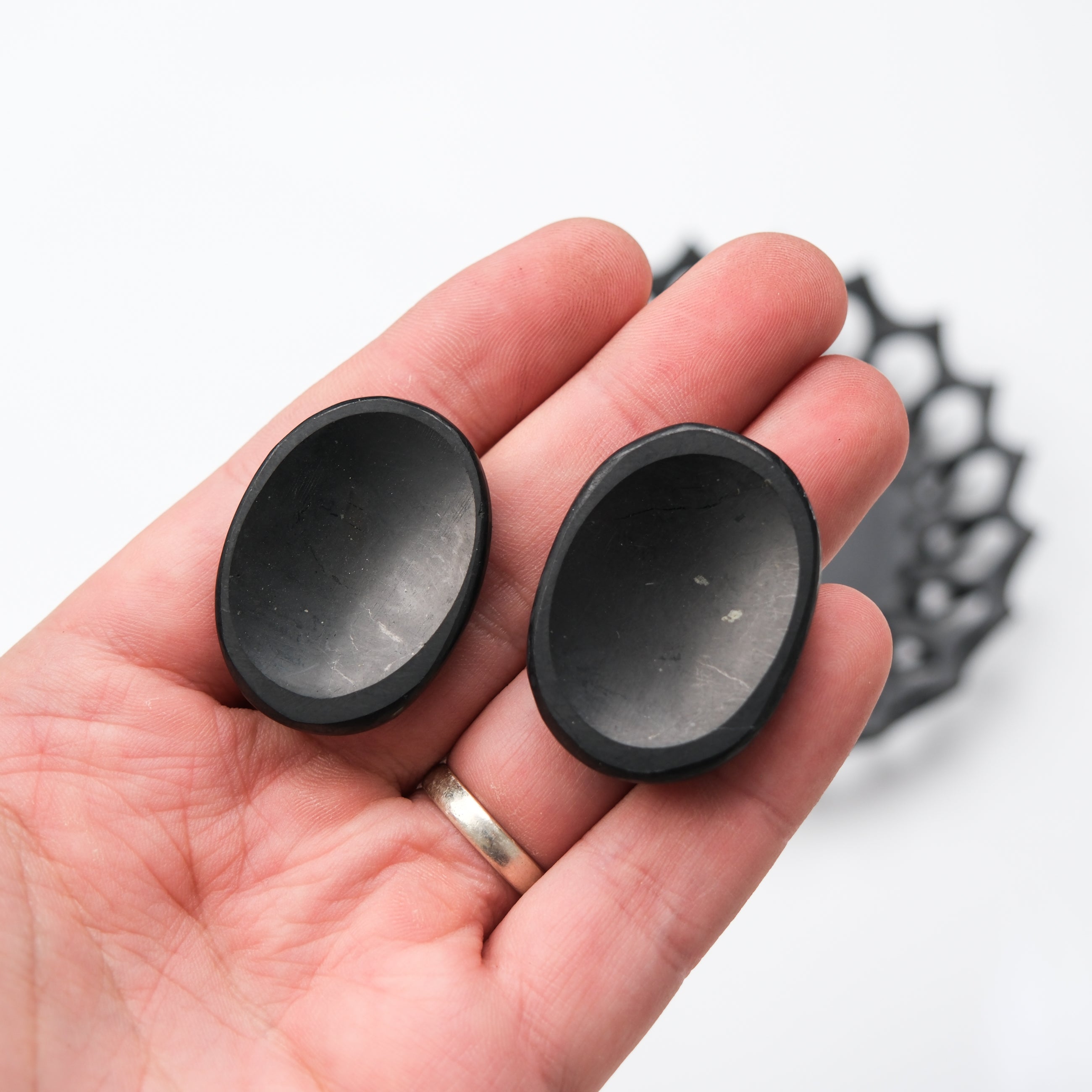 Shungite worry stone from Noctis Studio resting on a wooden surface with smooth, polished black stone texture.