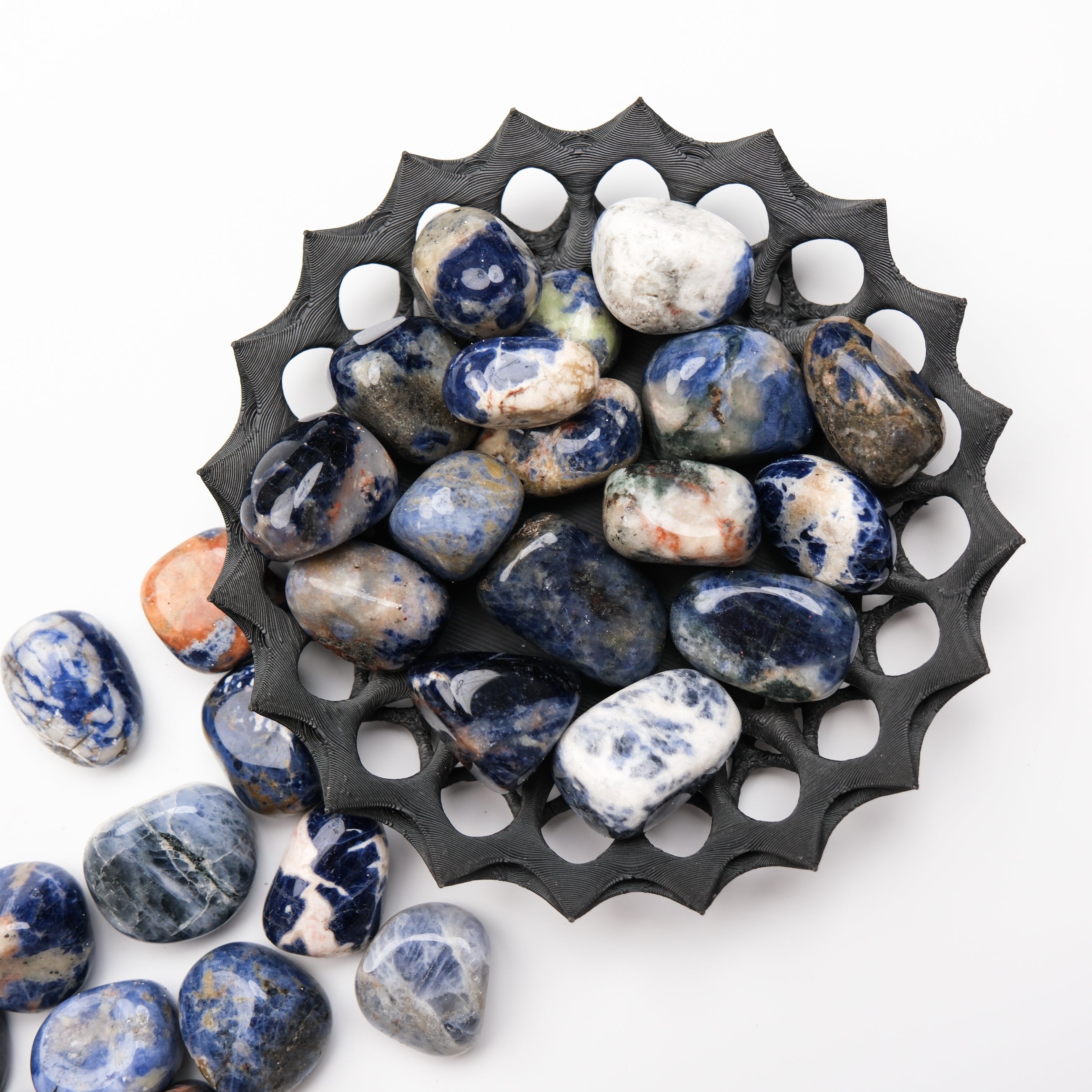 Sodalite tumble stone from Noctis Studio showing deep blue and white mineral patterns on a polished surface.