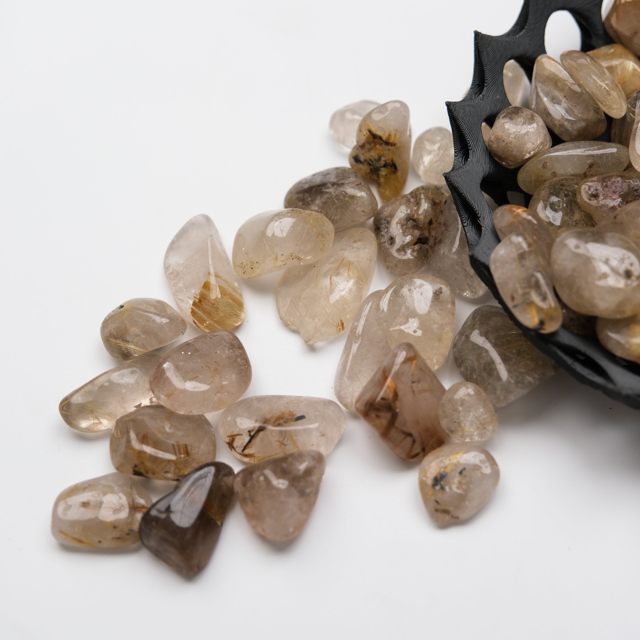 Golden Rutilated Quartz tumble stone from Noctis Studio, showcasing its shiny golden rutile inclusions and smooth polished surface.