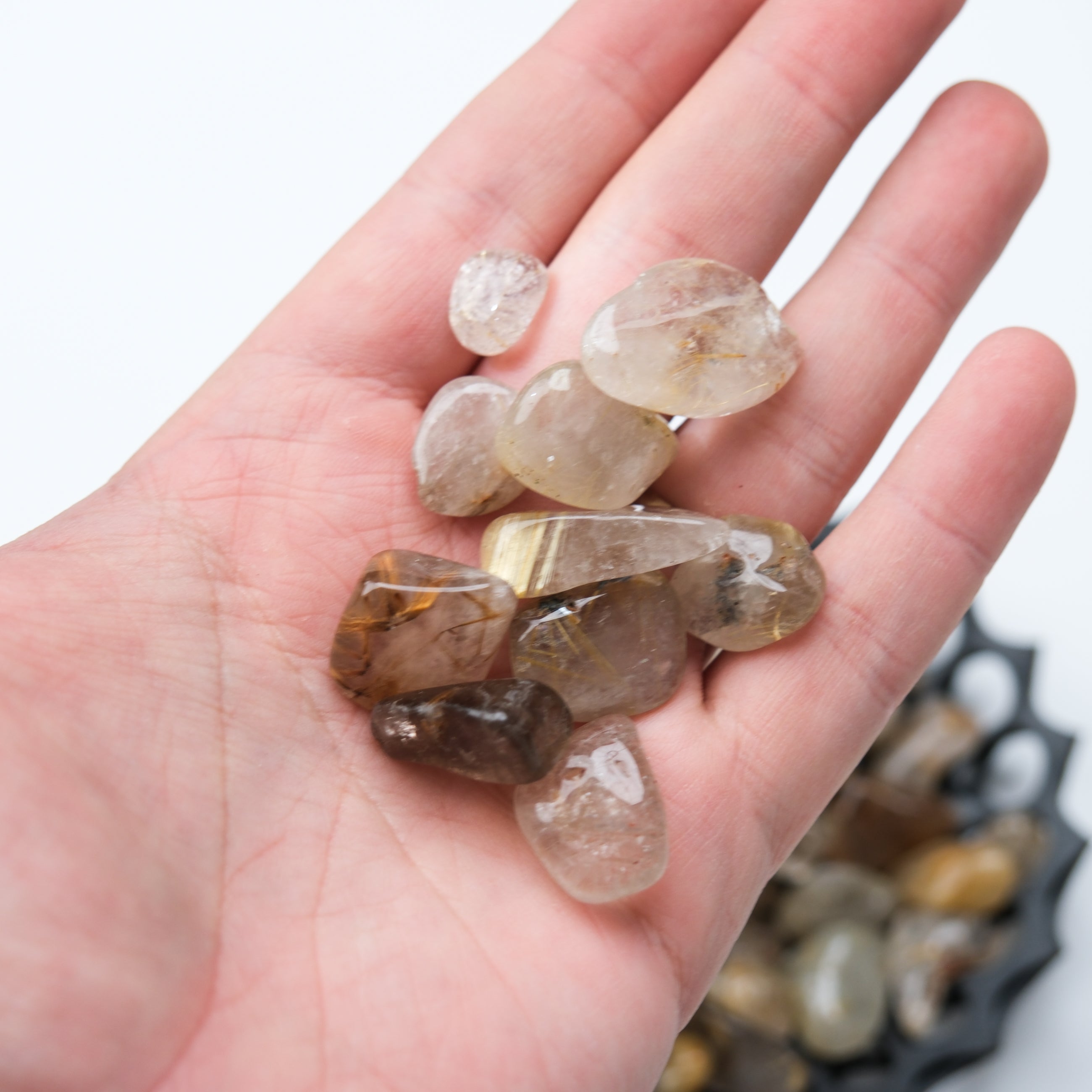 Golden Rutilated Quartz tumble stone from Noctis Studio, showing clear quartz with golden rutile inclusions and a polished smooth surface.