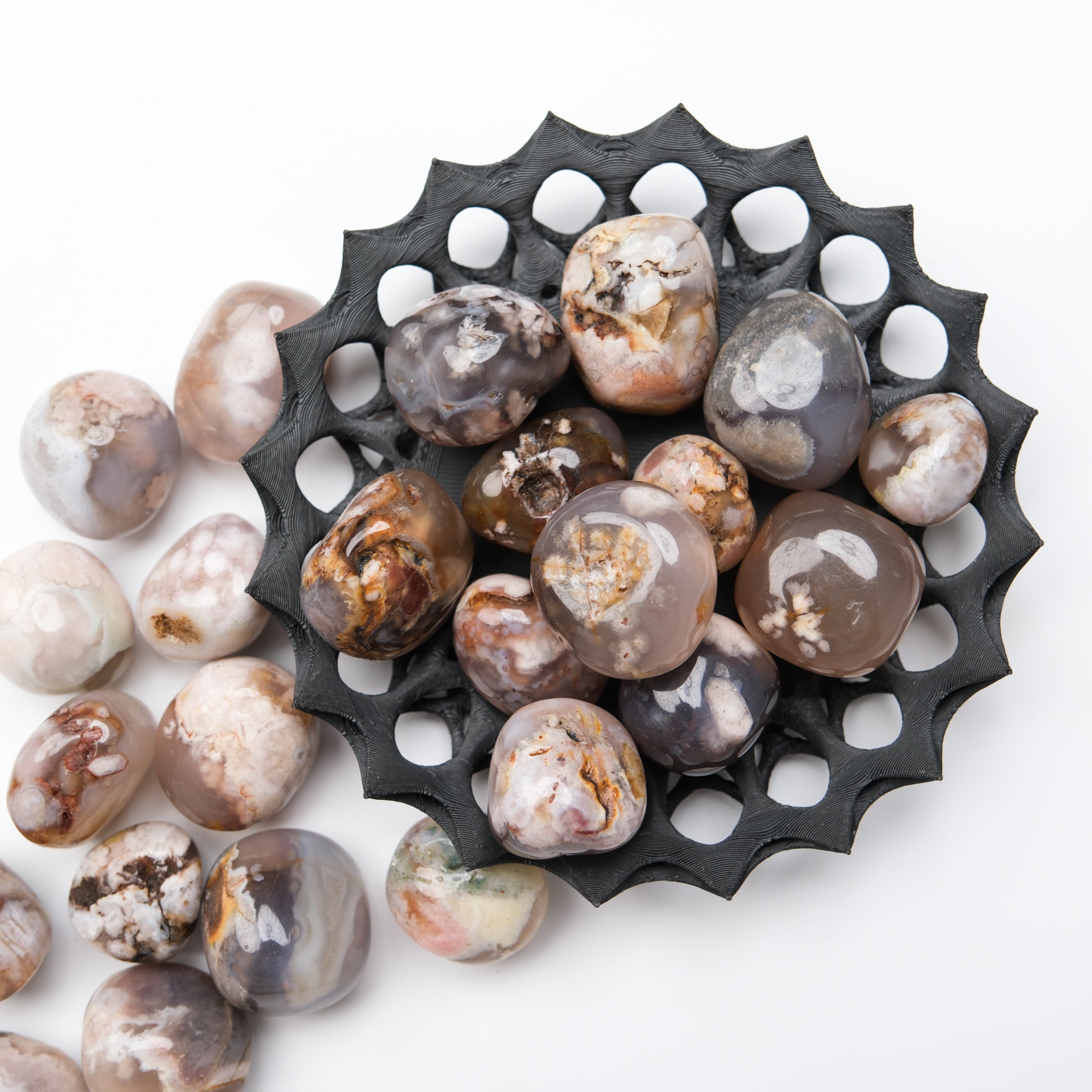 Black flower agate tumble stone from Noctis Studio, showcasing polished floral patterns and smooth, rounded gemstone surface.