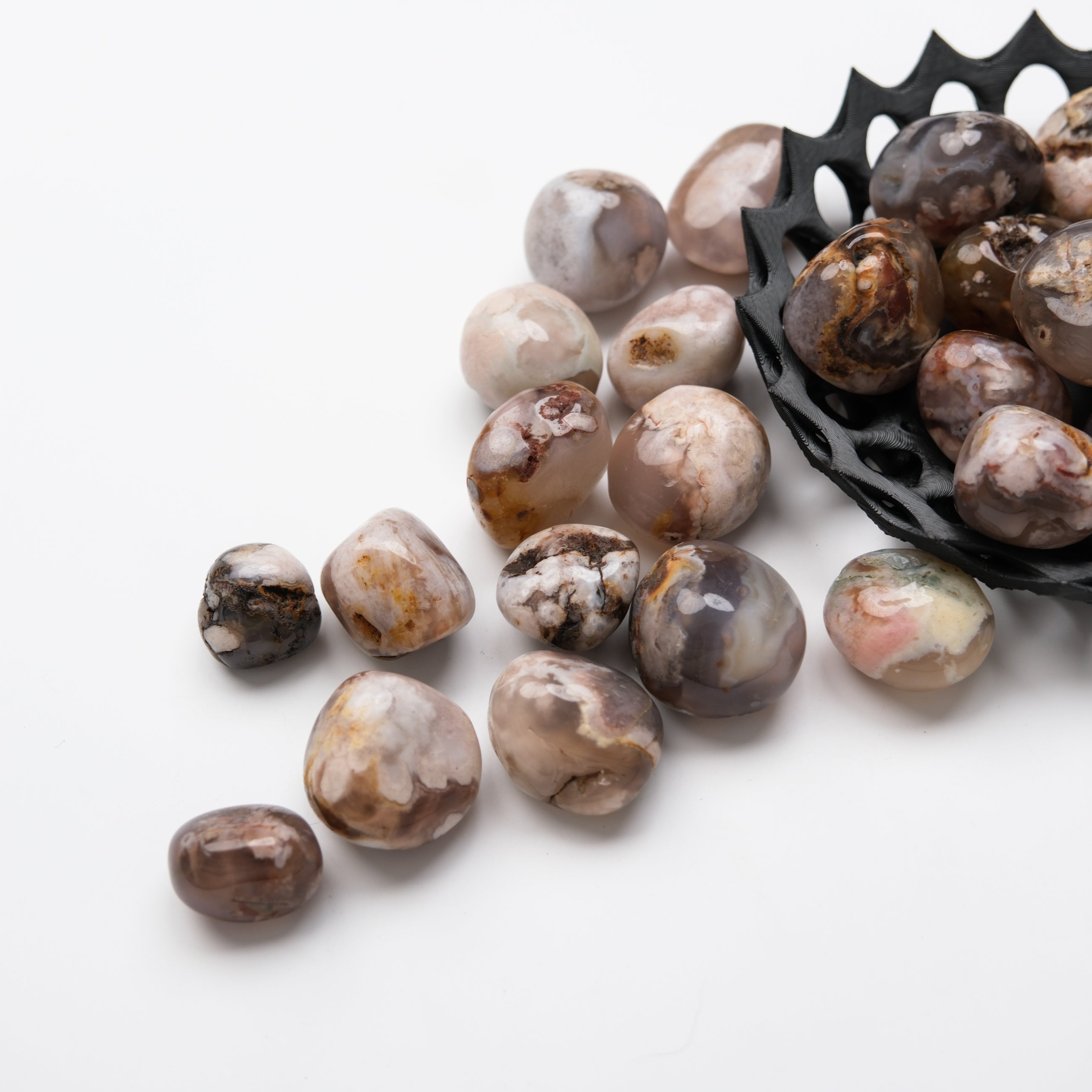 Black Flower Agate tumble stone from Noctis Studio, smooth polished gemstone with intricate floral patterns and deep black color.