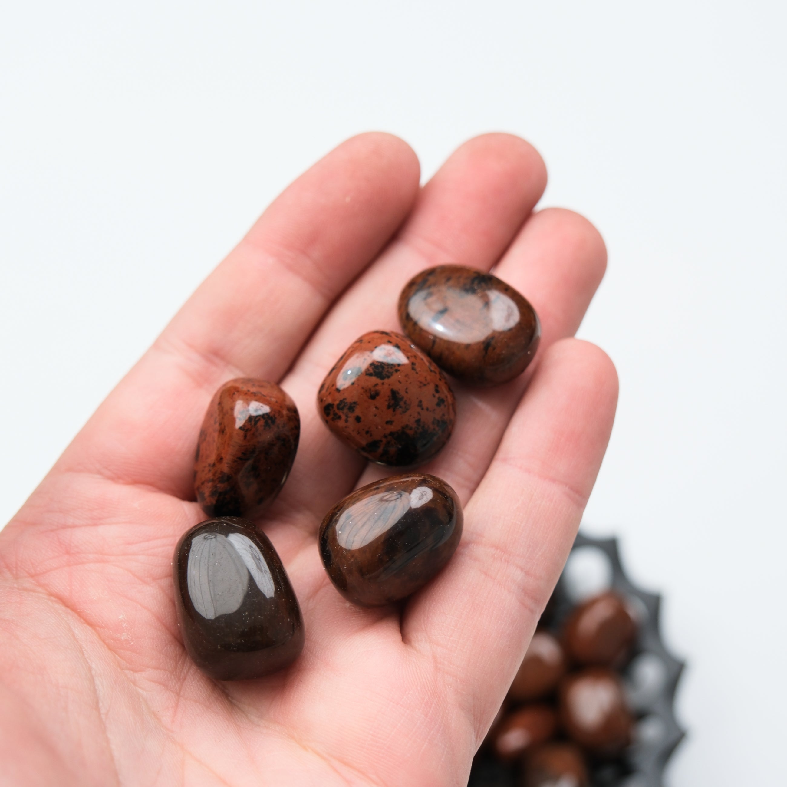 Mahogany Obsidian tumble stone from Noctis Studio, polished natural mineral with deep red and black swirls, smooth surface.