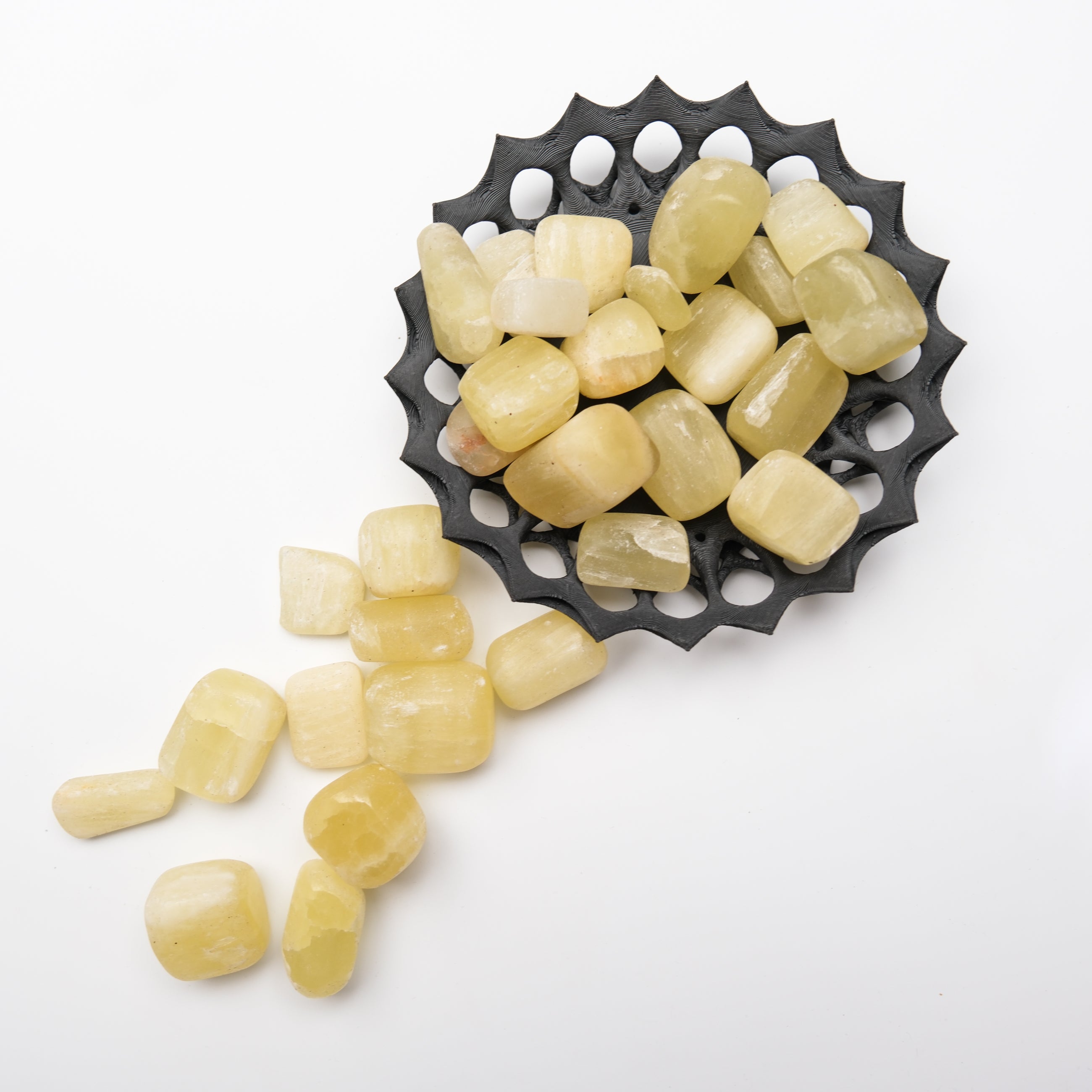 Lemon calcite tumble stone from Noctis Studio with polished, smooth surface showing vibrant yellow color and natural stone details.