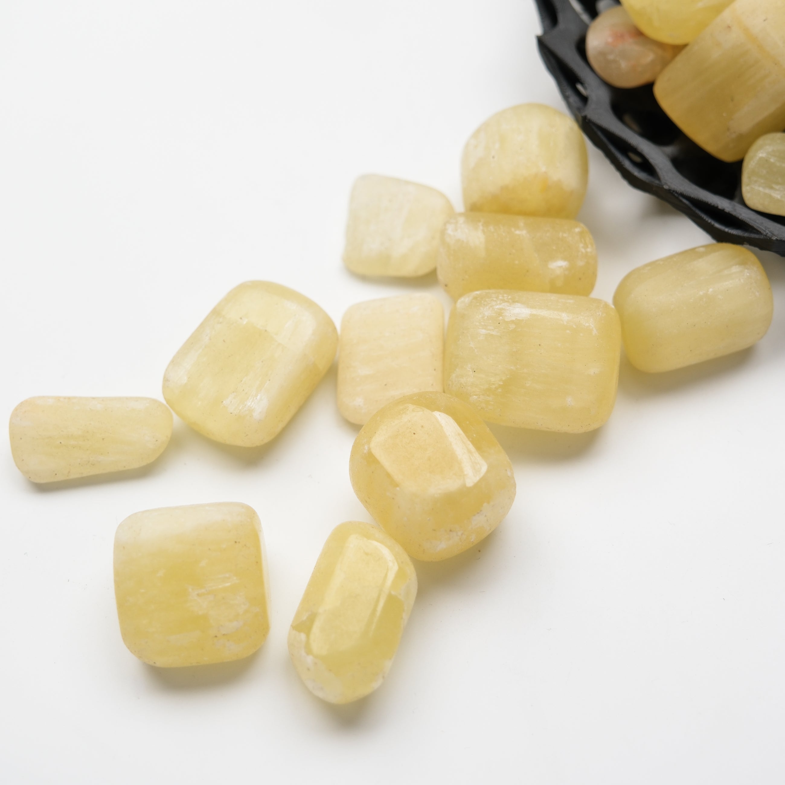 Lemon Calcite tumble stone from Noctis Studio showing vibrant yellow mineral with smooth, polished surface.