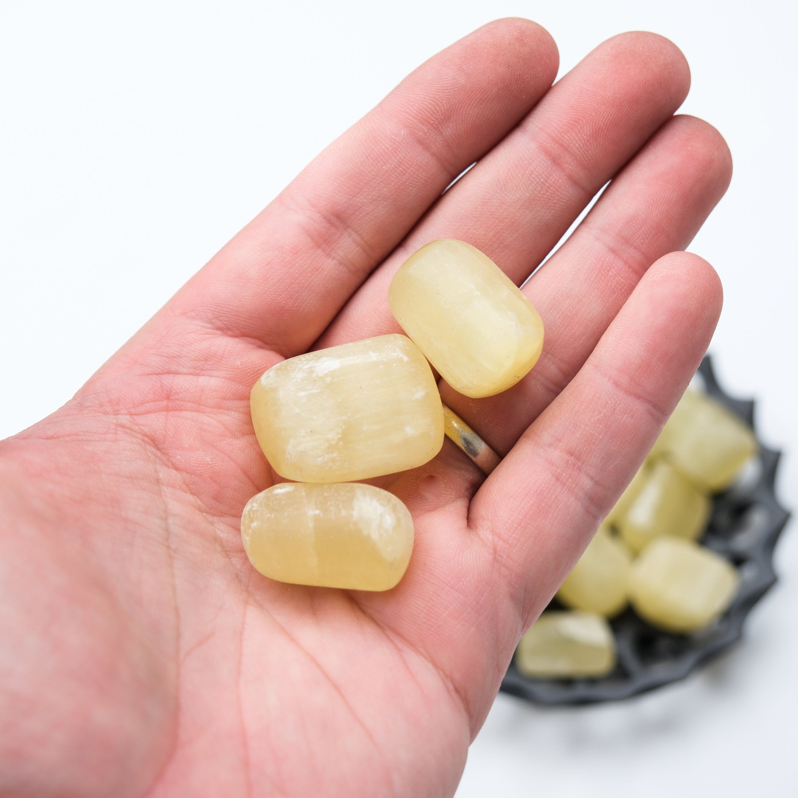 Lemon Calcite tumble stone from Noctis Studio, showcasing a polished, vibrant yellow mineral with smooth, rounded edges.