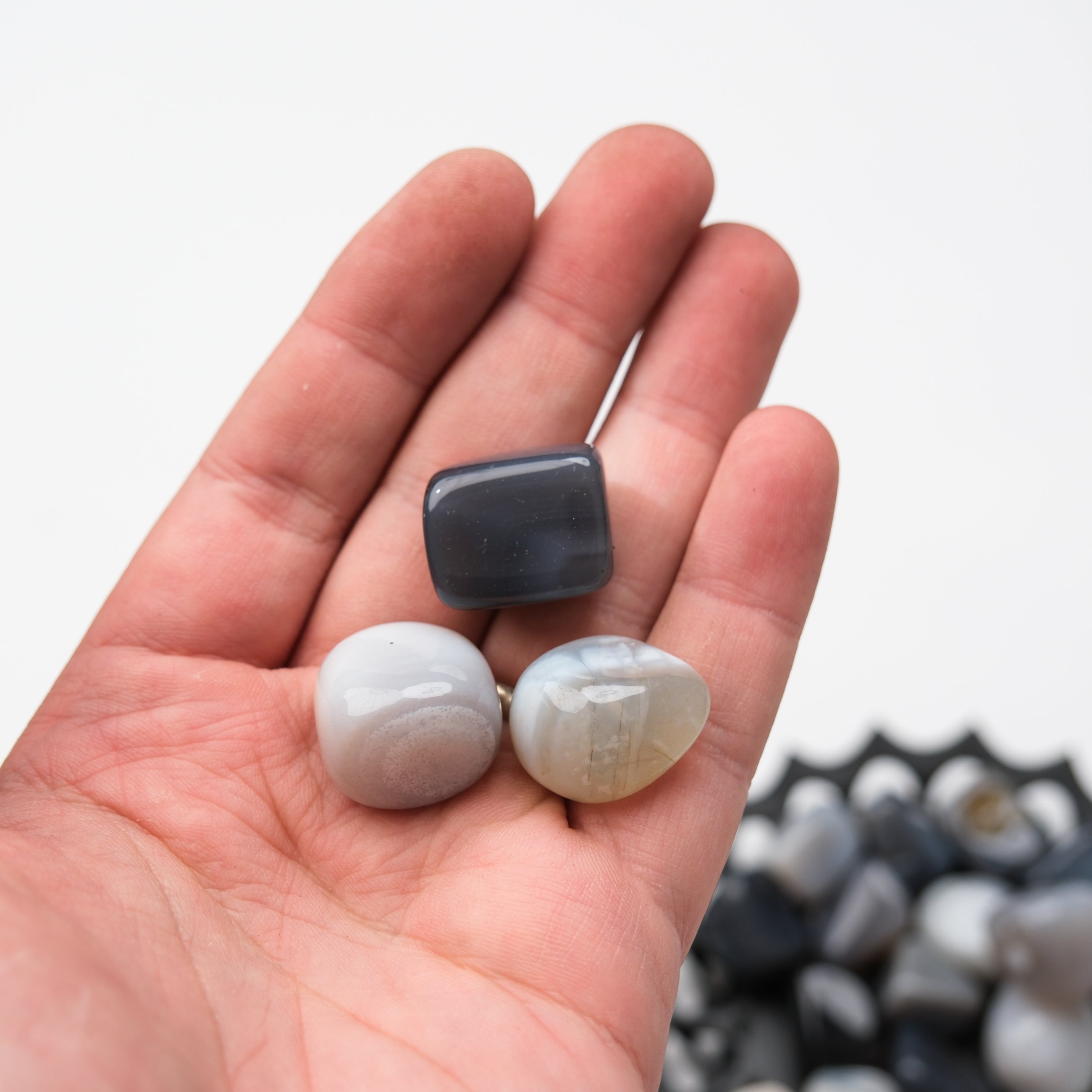Gray agate tumble stone from Noctis Studio, smooth polished mineral with natural banding and unique stone patterning.