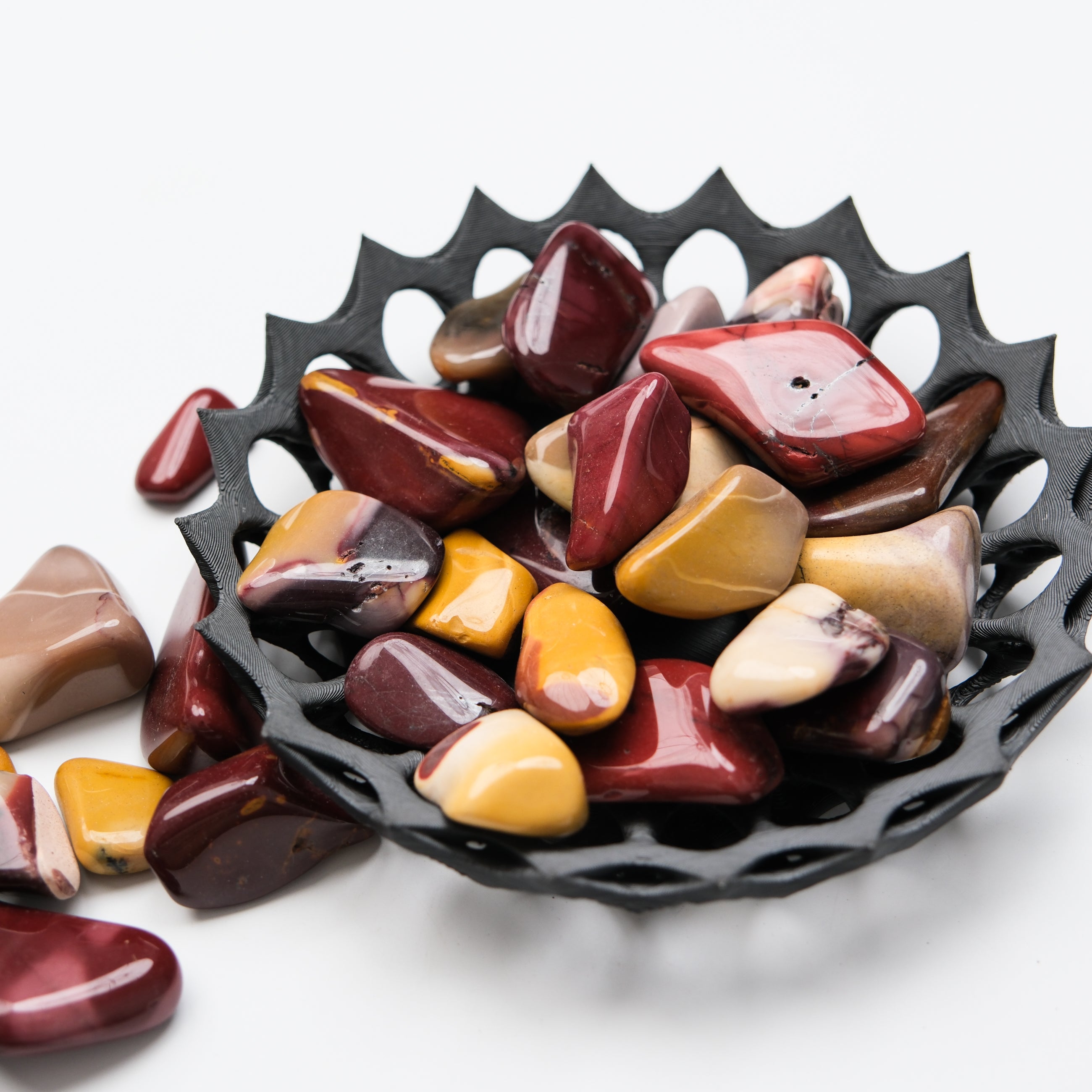 Mookaite tumble stone from Noctis Studio showing earthy red and yellow hues, polished and smooth with natural stone texture.