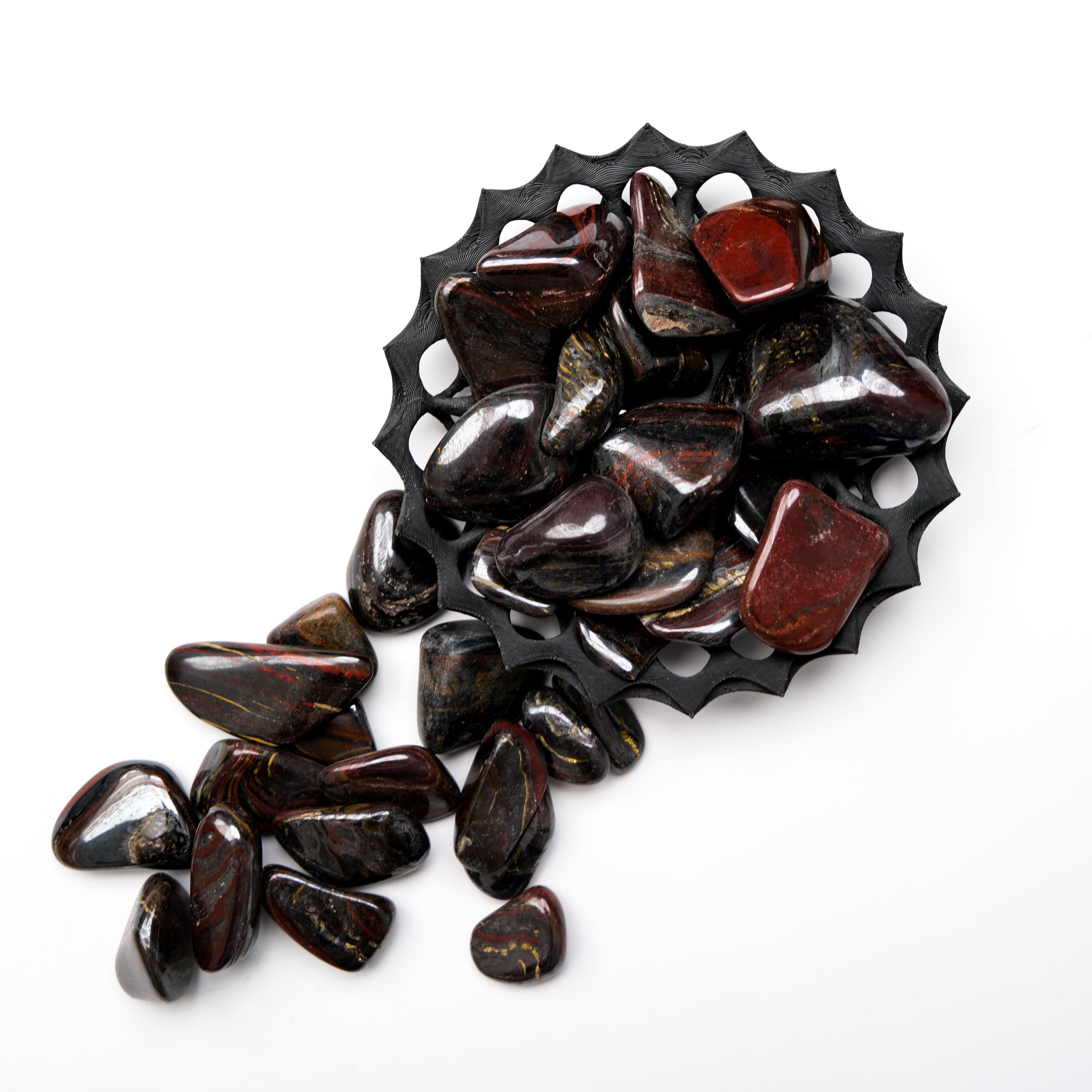 Red Tigers iron tumble stone from Noctis Studio, showcasing a polished, vibrant red gemstone with natural patterns.