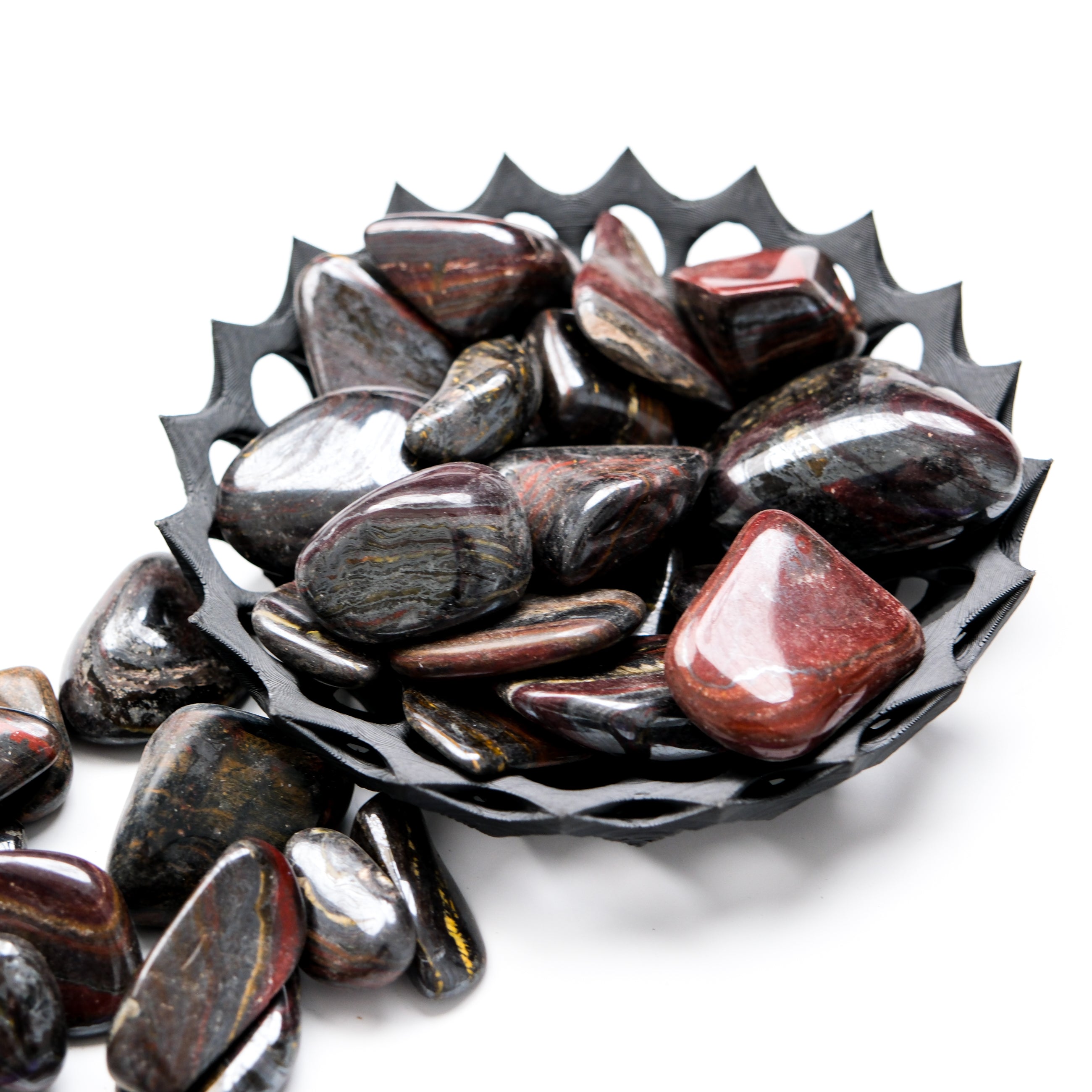 Red Tigers Iron Tumble Stone from Noctis Studio, smooth polished gemstone with vibrant red and black tiger stripe patterns.