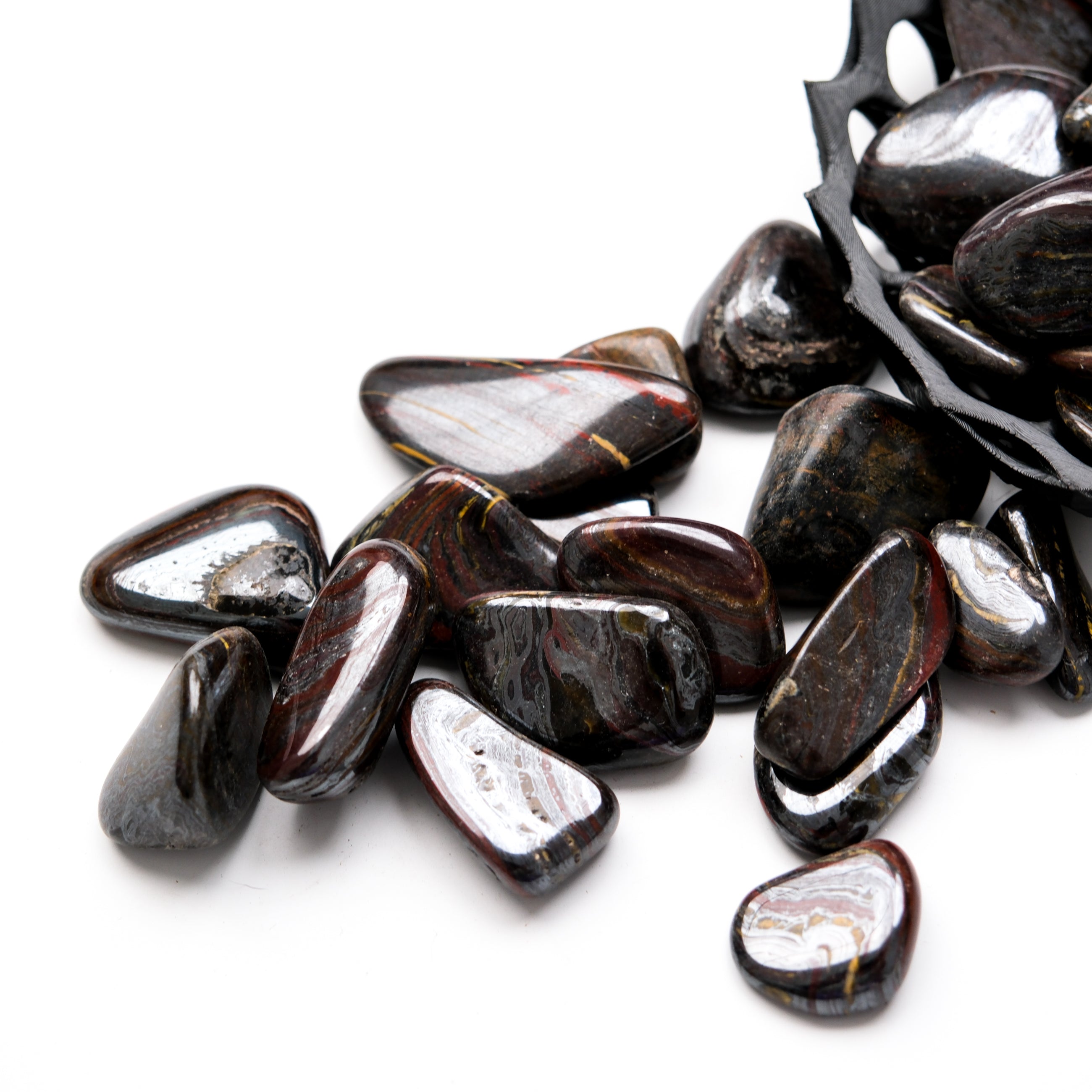 Red Tigers Iron Tumble Stone from Noctis Studio, polished gemstone with vibrant red and black tiger stripe patterns.