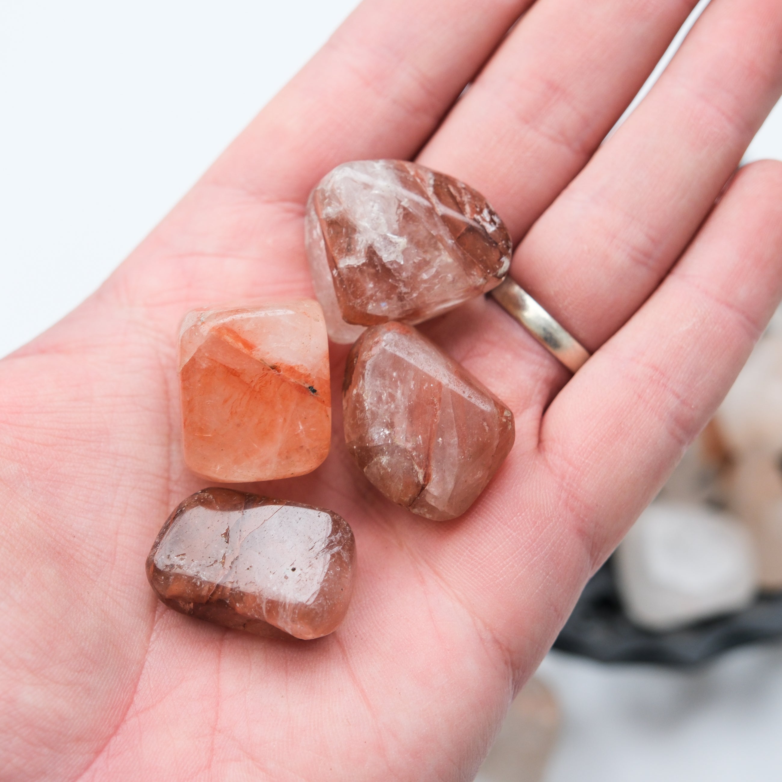 Hematoid Quartz tumble stone from Noctis Studio showing a polished, rounded gemstone with red and earthy mineral streaks.