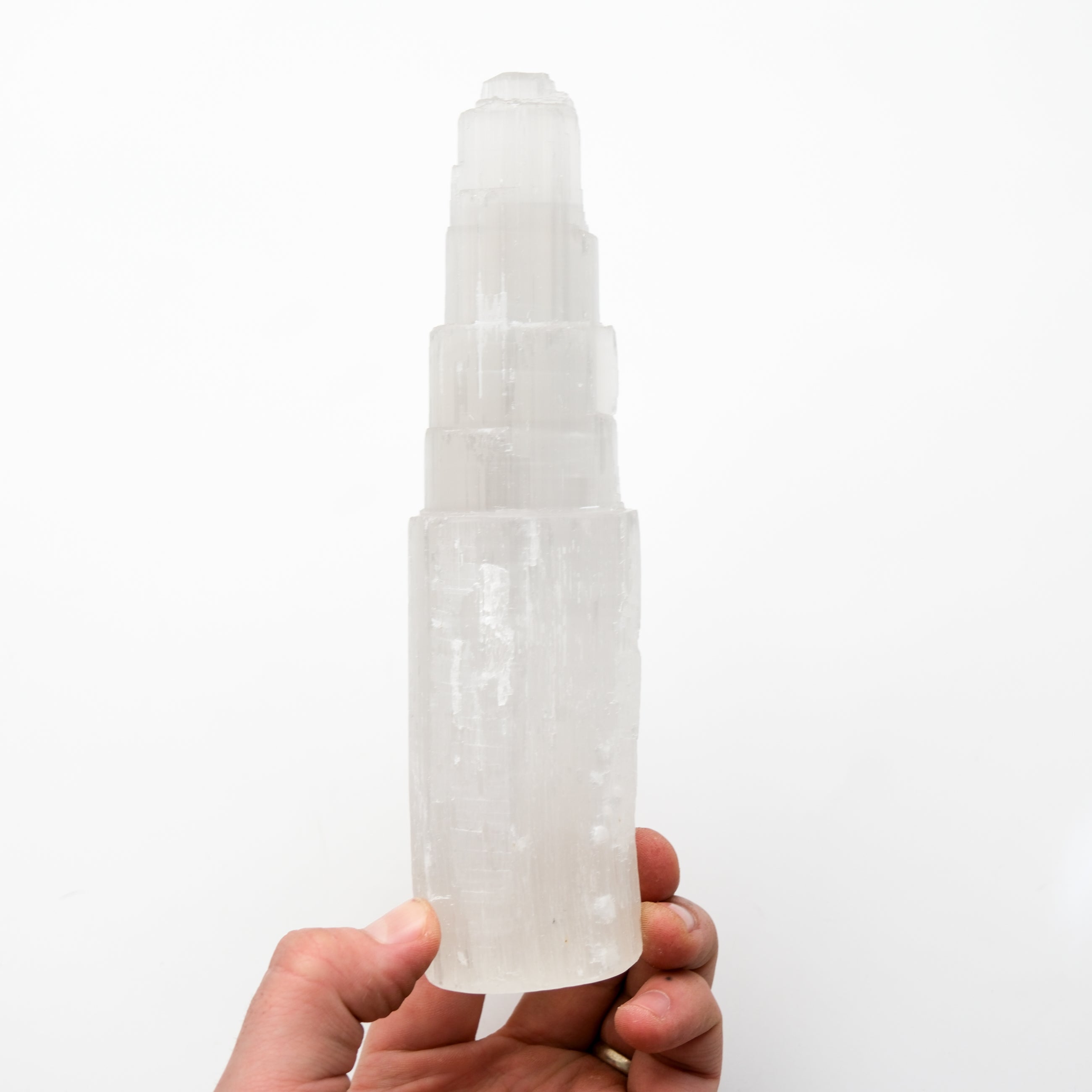 Noctis Studio selenite pillar crystal with smooth, natural white surface and subtle glow, standing upright on a flat surface.