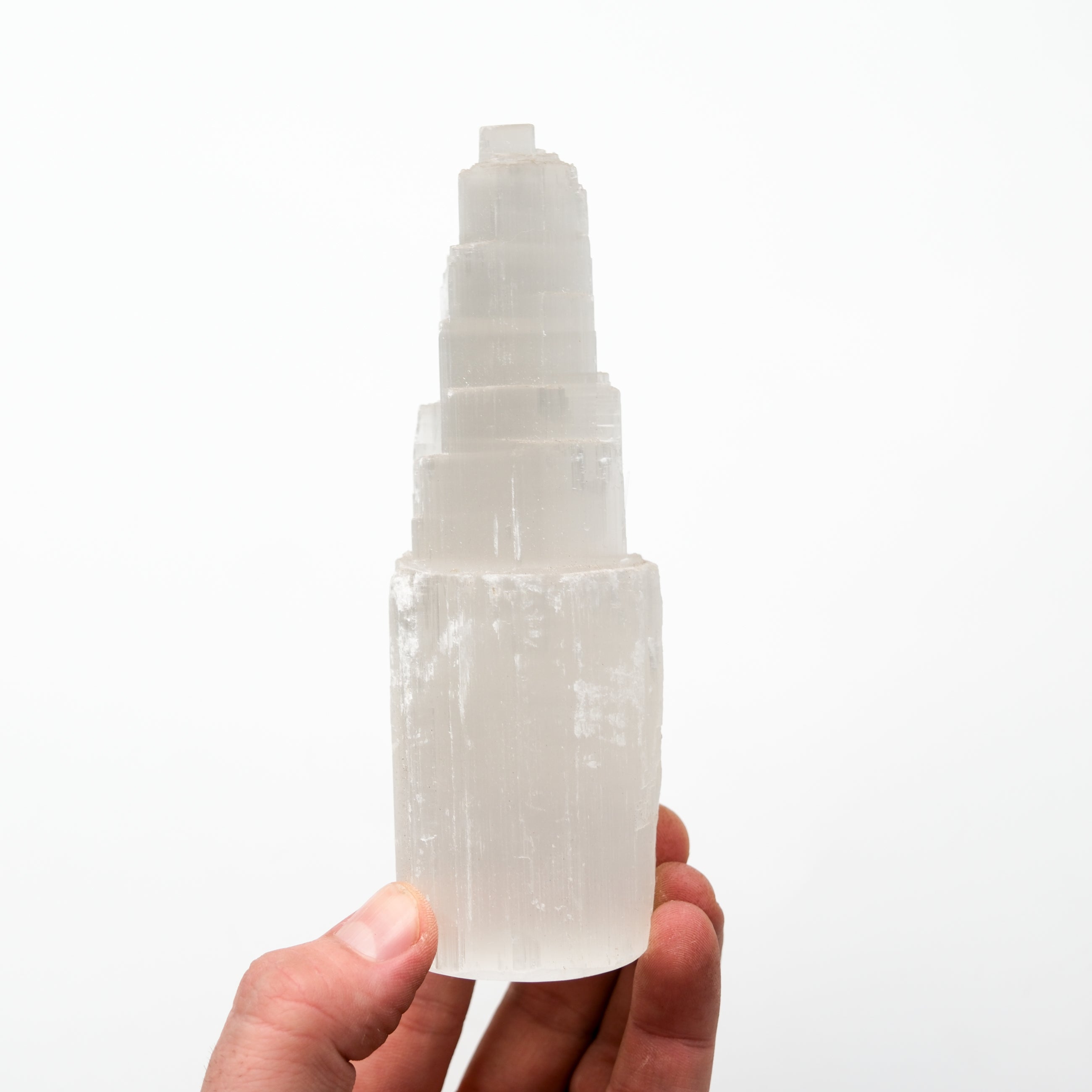Selenite pillar crystal from Noctis Studio, smooth white mineral block with natural striations, standing upright on a flat surface.