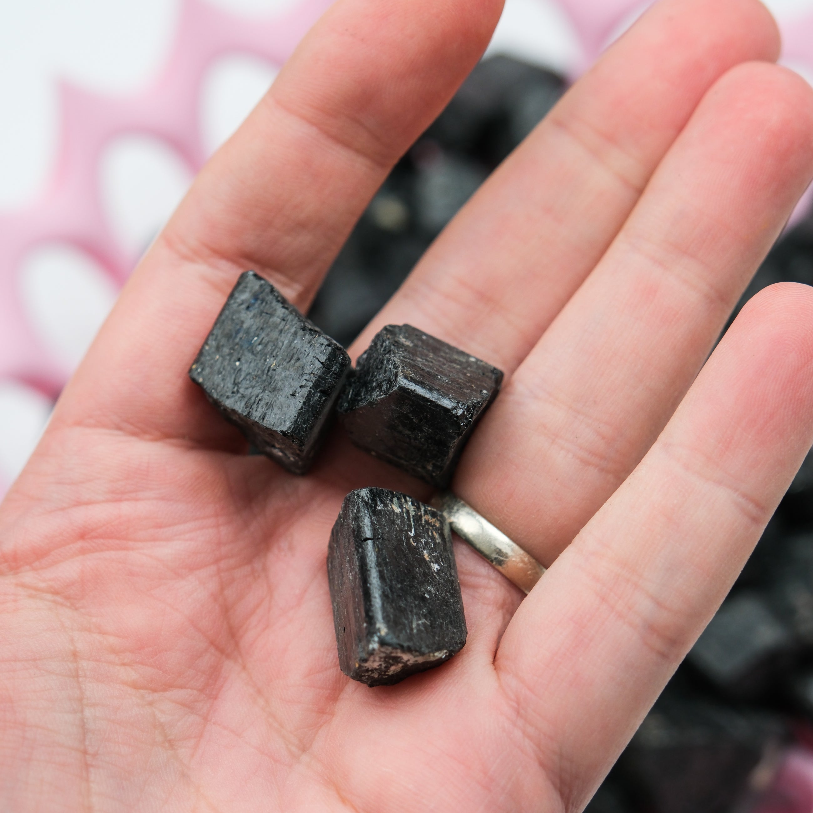 Rough black tourmaline stone from Noctis Studio with natural, textured surface and deep black color on a white background.