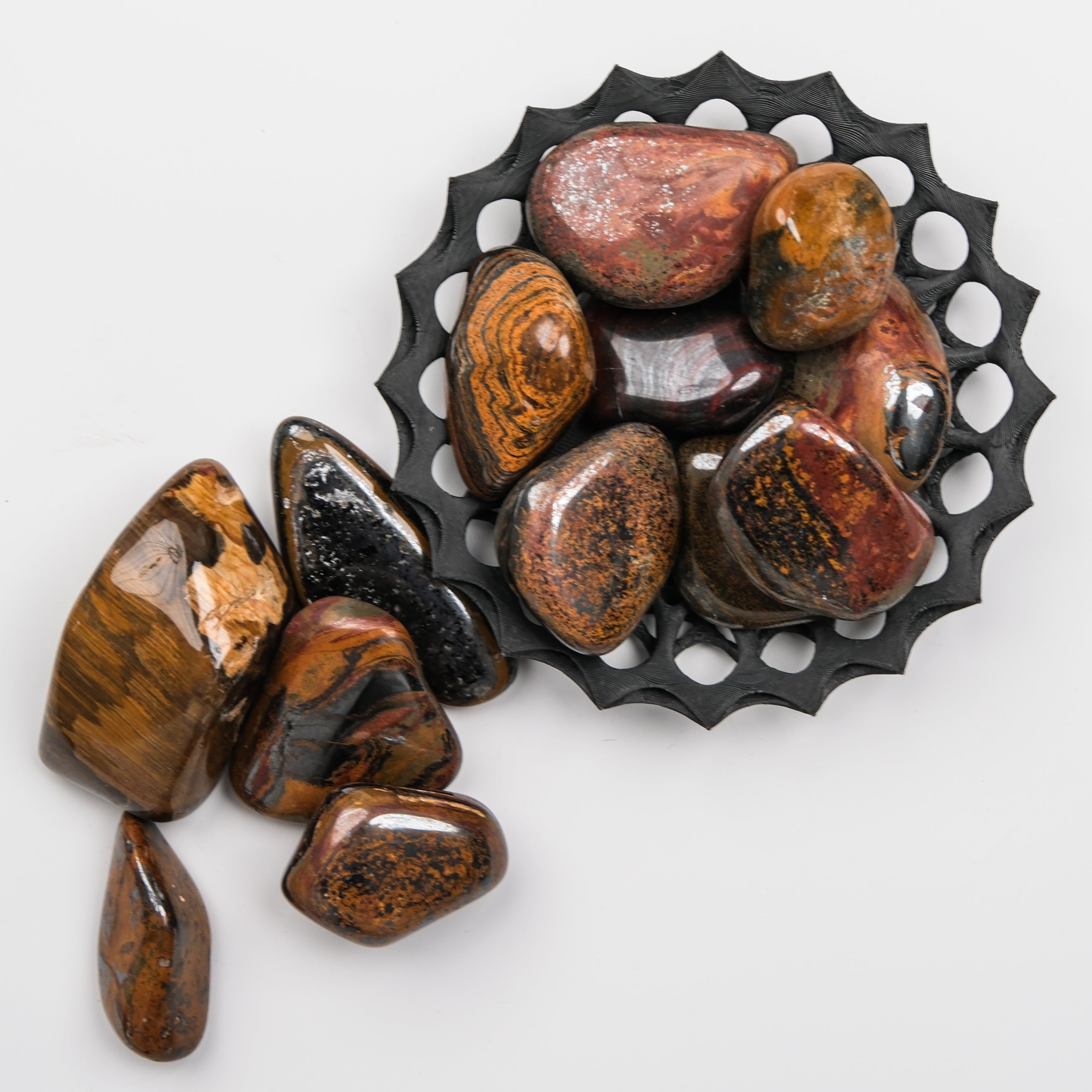 Noctis Studio Tigers Iron Tumble Stone, polished mineral with vibrant orange and black tiger stripe pattern, on display.