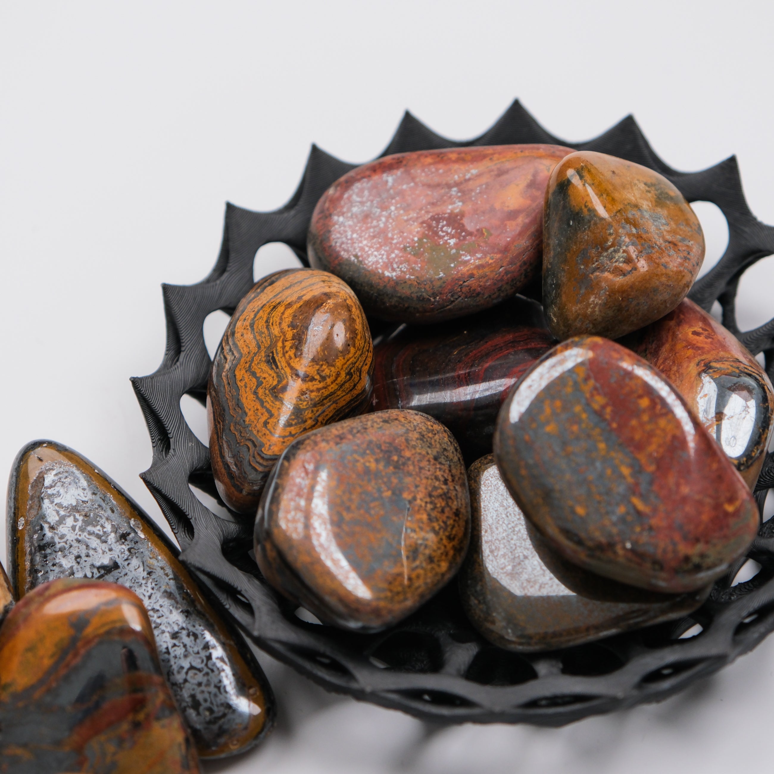 Tigers Iron Tumble Stone from Noctis Studio, smooth polished mineral specimen with distinctive tiger stripe patterns.