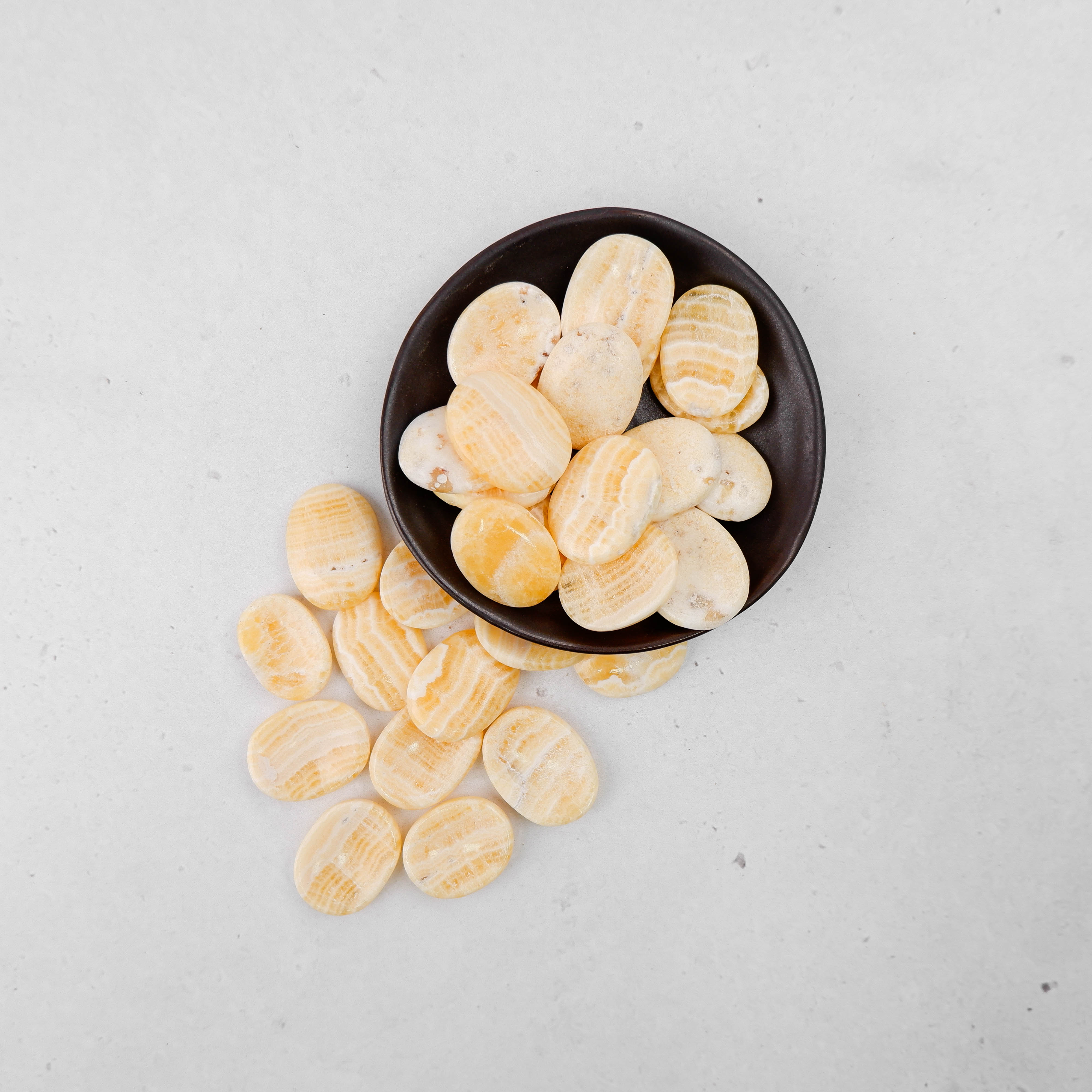 Orange banded calcite worry stone by Noctis Studio, smooth polished gemstone with vibrant orange and white banding.