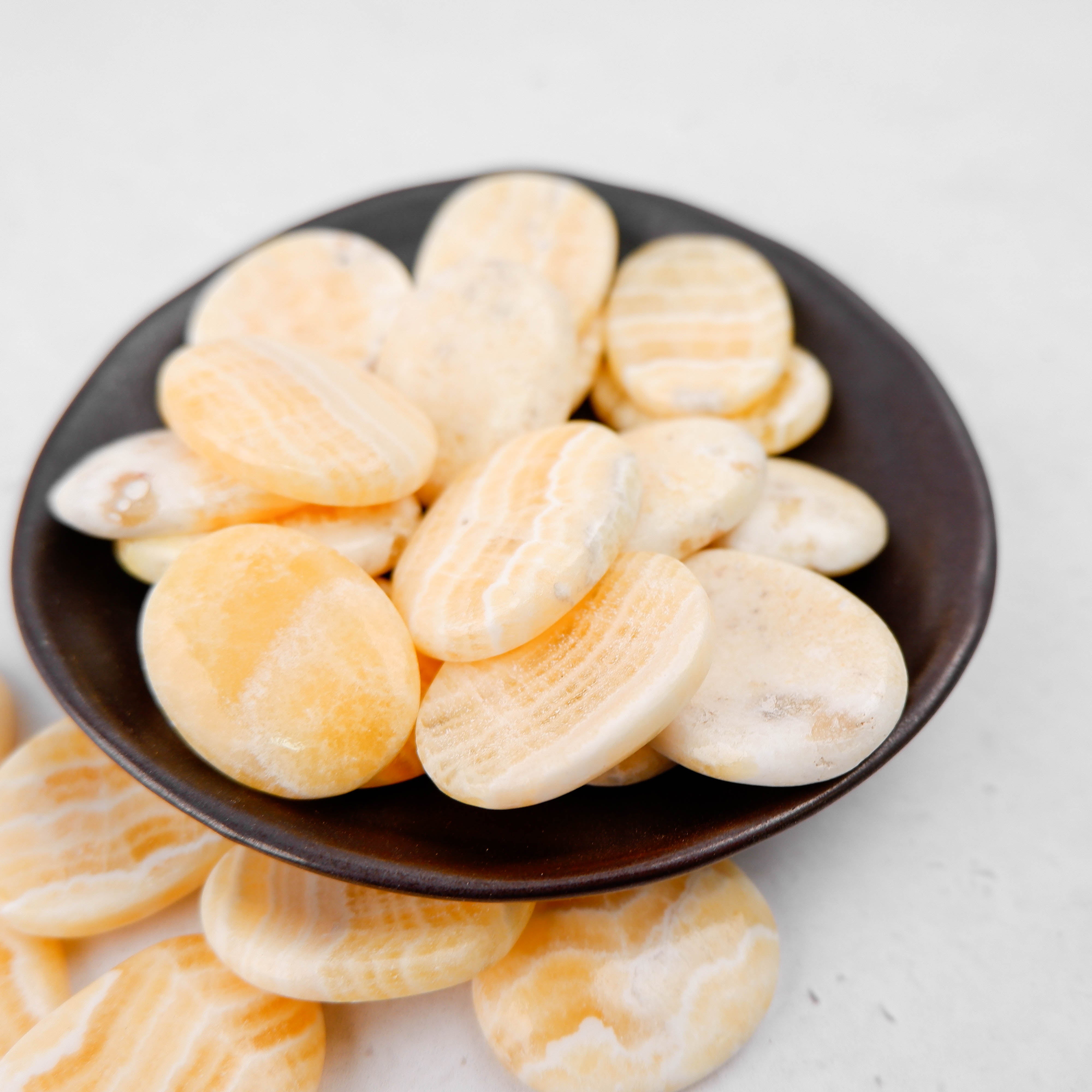 Orange banded calcite worry stone from Noctis Studio, smooth polished gemstone with vibrant orange and white banding.